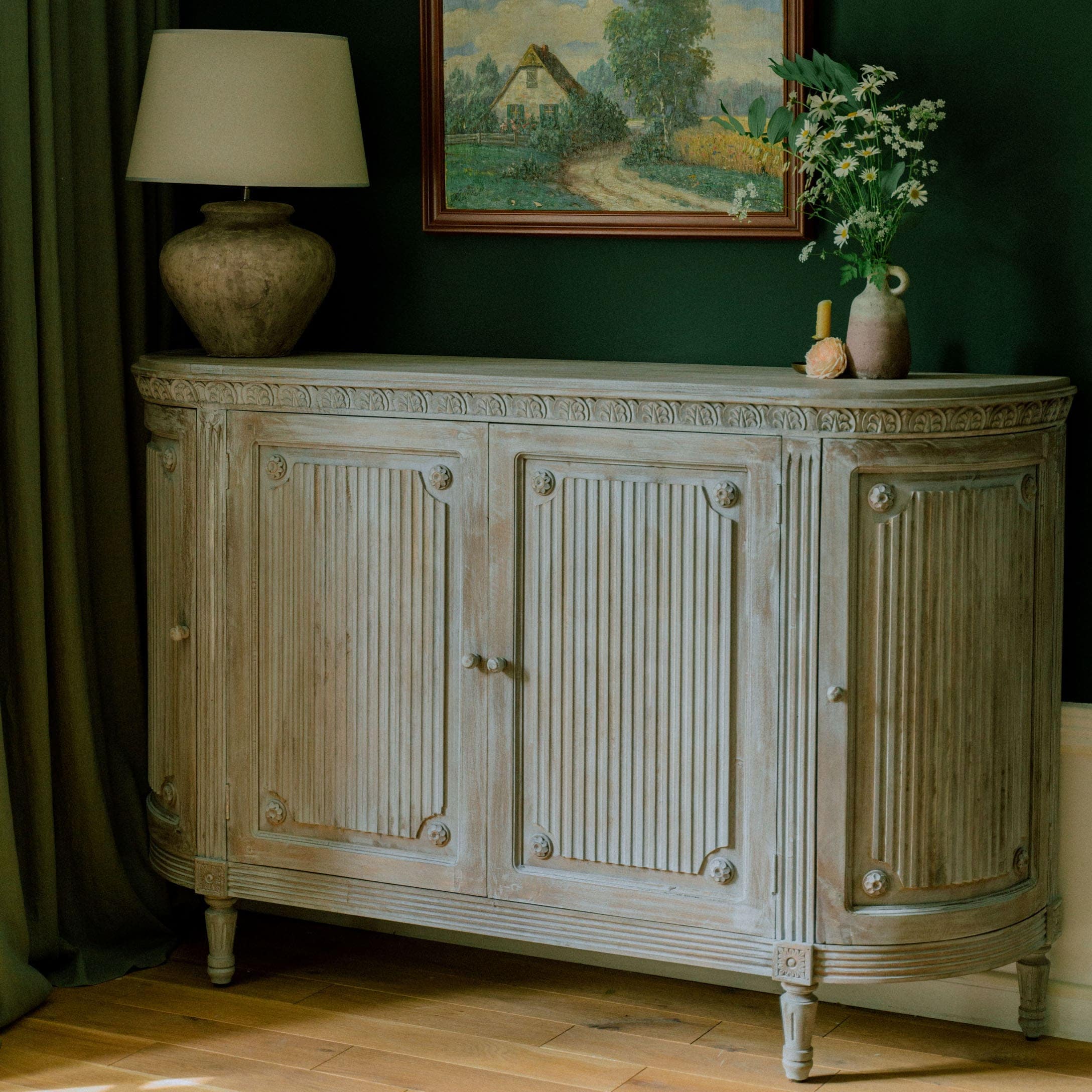 Buffet en bois clair avec détails sculptés et décorations florales dans un intérieur élégant