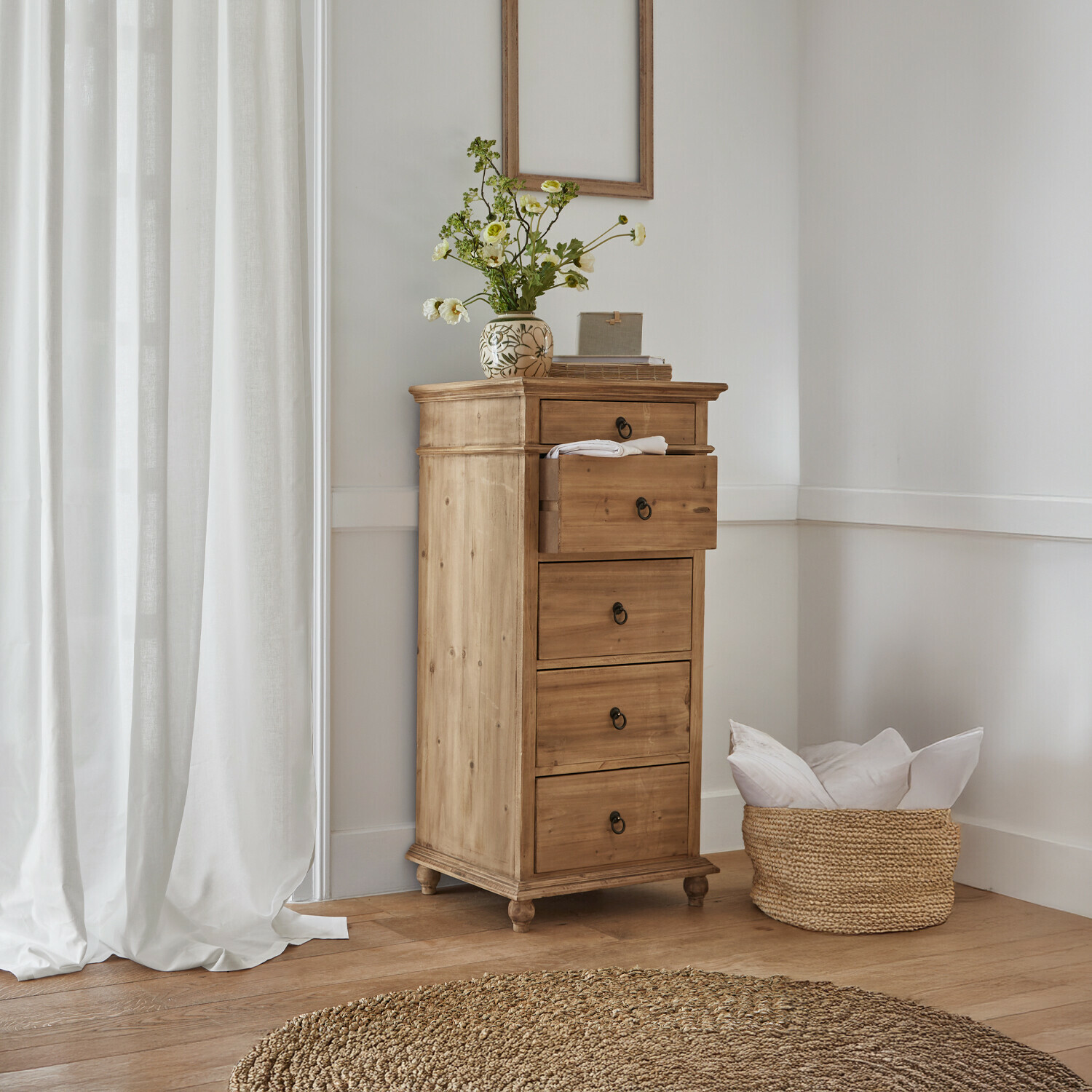 Commode Yewbridge Commode haute en bois de pin naturel avec quatre tiroirs et vase décoratif dans un intérieur lumineux