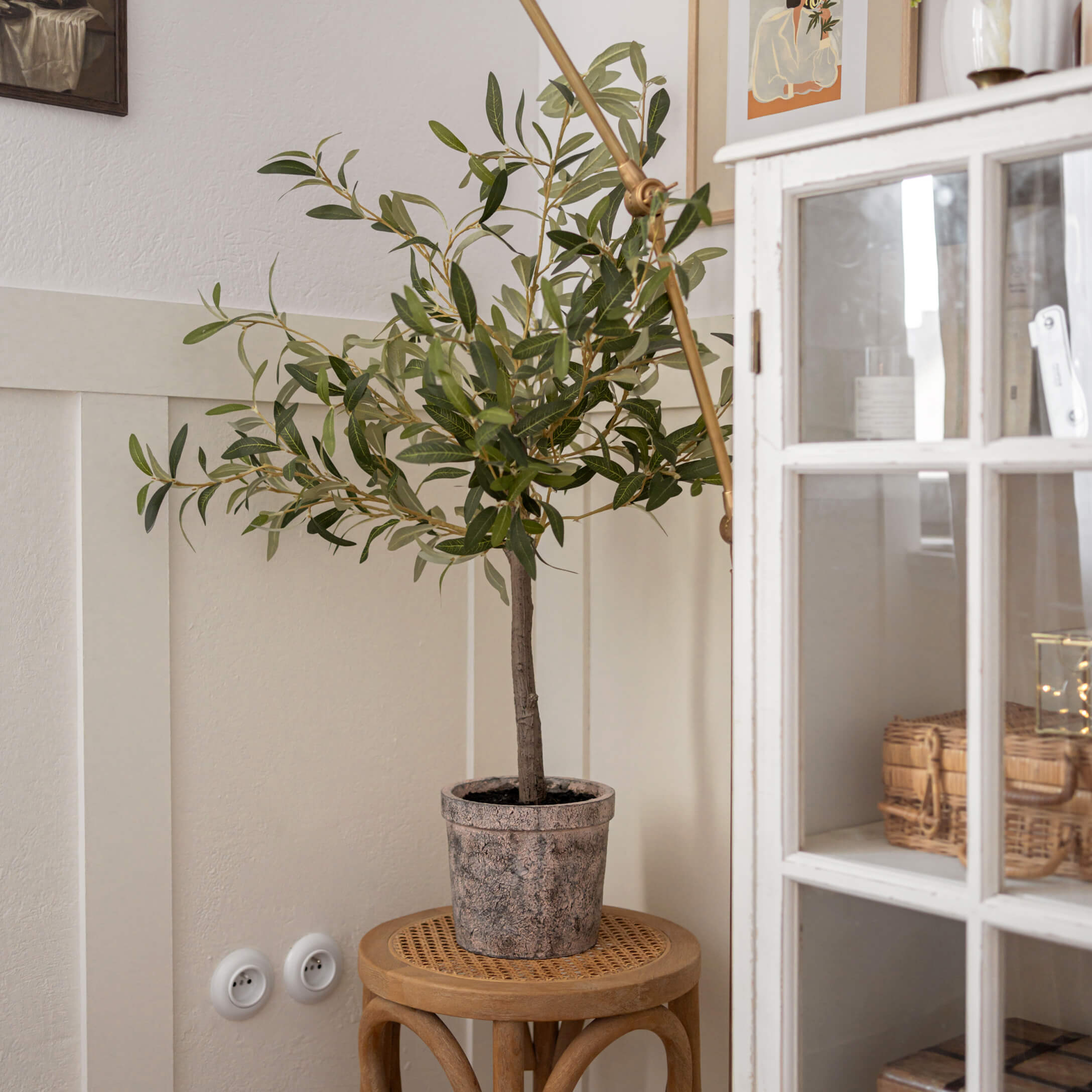 Arbre d'olivier artificiel en pot en pierre sur un tabouret en bois dans un intérieur clair