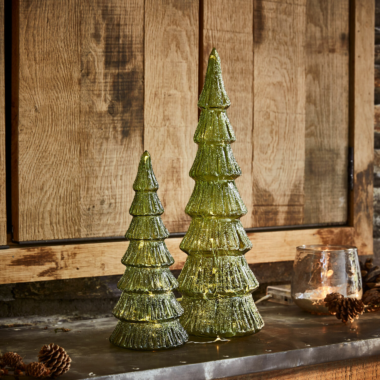 Lot de 2 arbres à LED Merrton Deux décorations de sapin en verre vert avec éclairage LED sur fond en bois, décorations de Noël