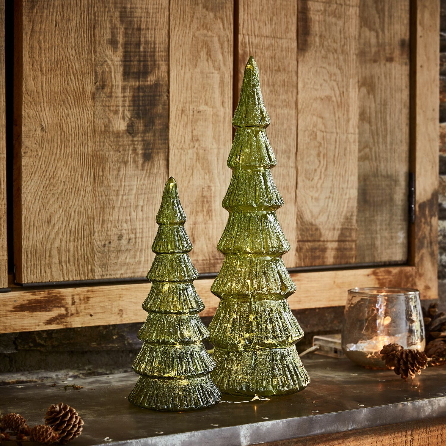 Lot de 2 arbres à LED Merrton Deux décorations de sapin en verre vert avec éclairage LED sur fond en bois, décorations de Noël