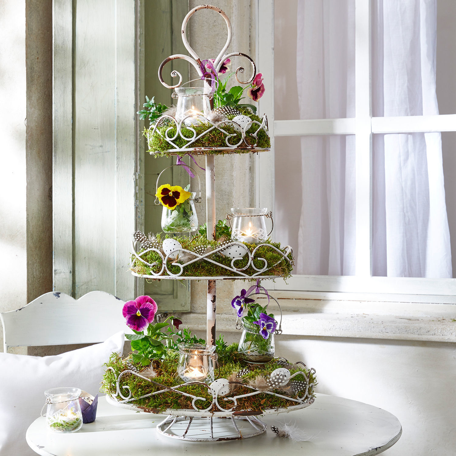 Étagère Julye Présentoir à trois niveaux en métal blanc avec mousse, fleurs et bougies décoratives sur table blanche