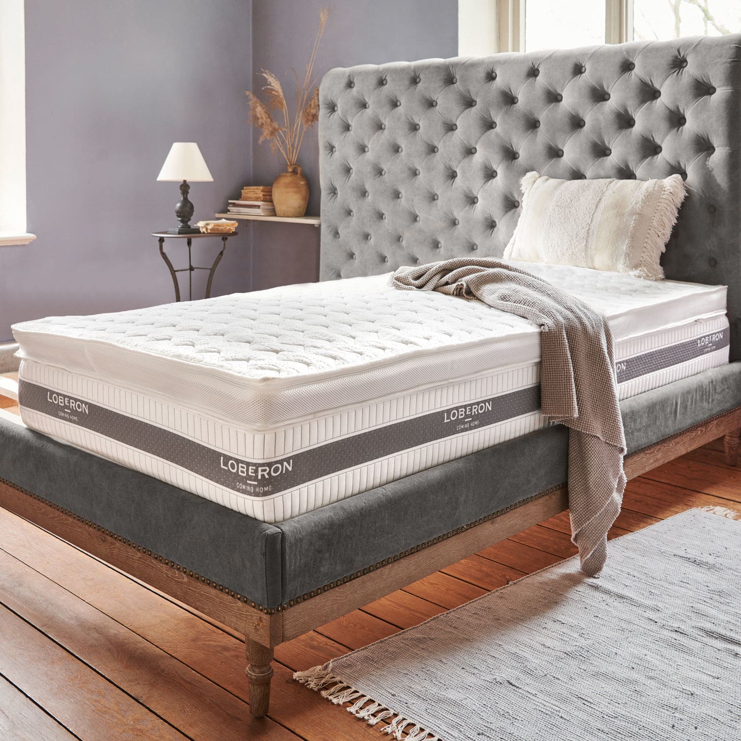 Surmatelas Danisar Cadre de lit rembourré gris avec matelas blanc Loberon et couverture beige dans une chambre chaleureuse