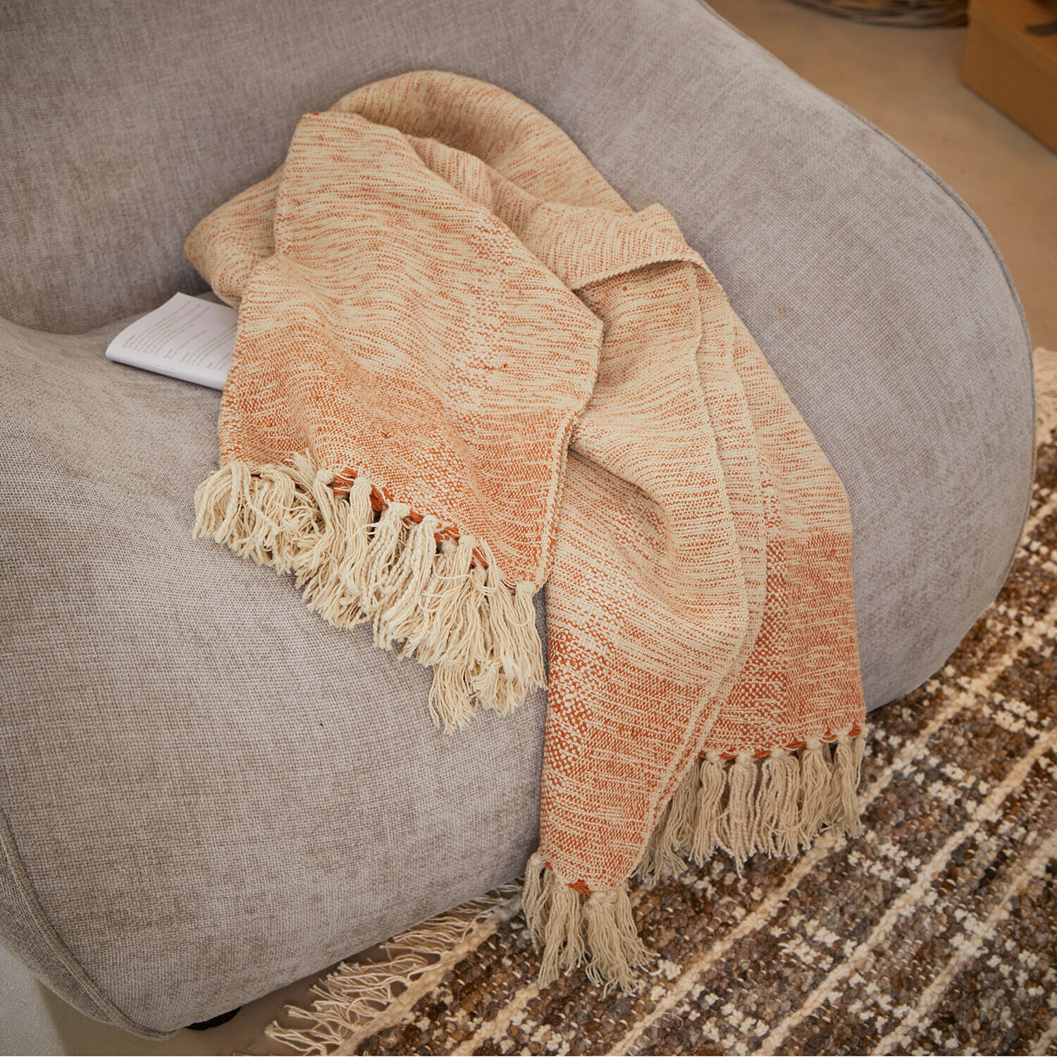 Plaid Winlow Plaid beige et orange avec franges sur fauteuil gris, tissu doux pour décoration intérieure