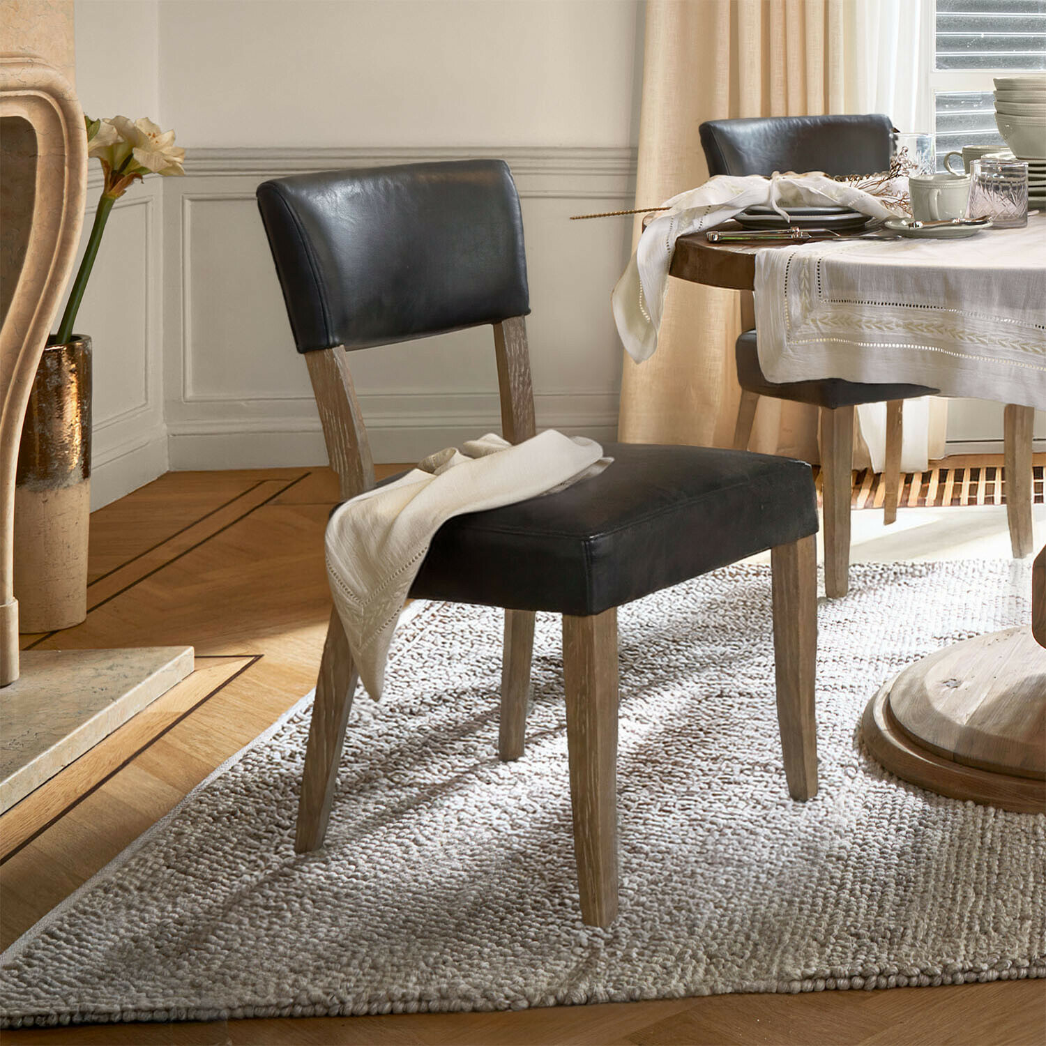 Chaise Norevaux Chaise de salle à manger en cuir noir avec pieds en bois sur tapis clair dans une pièce élégante