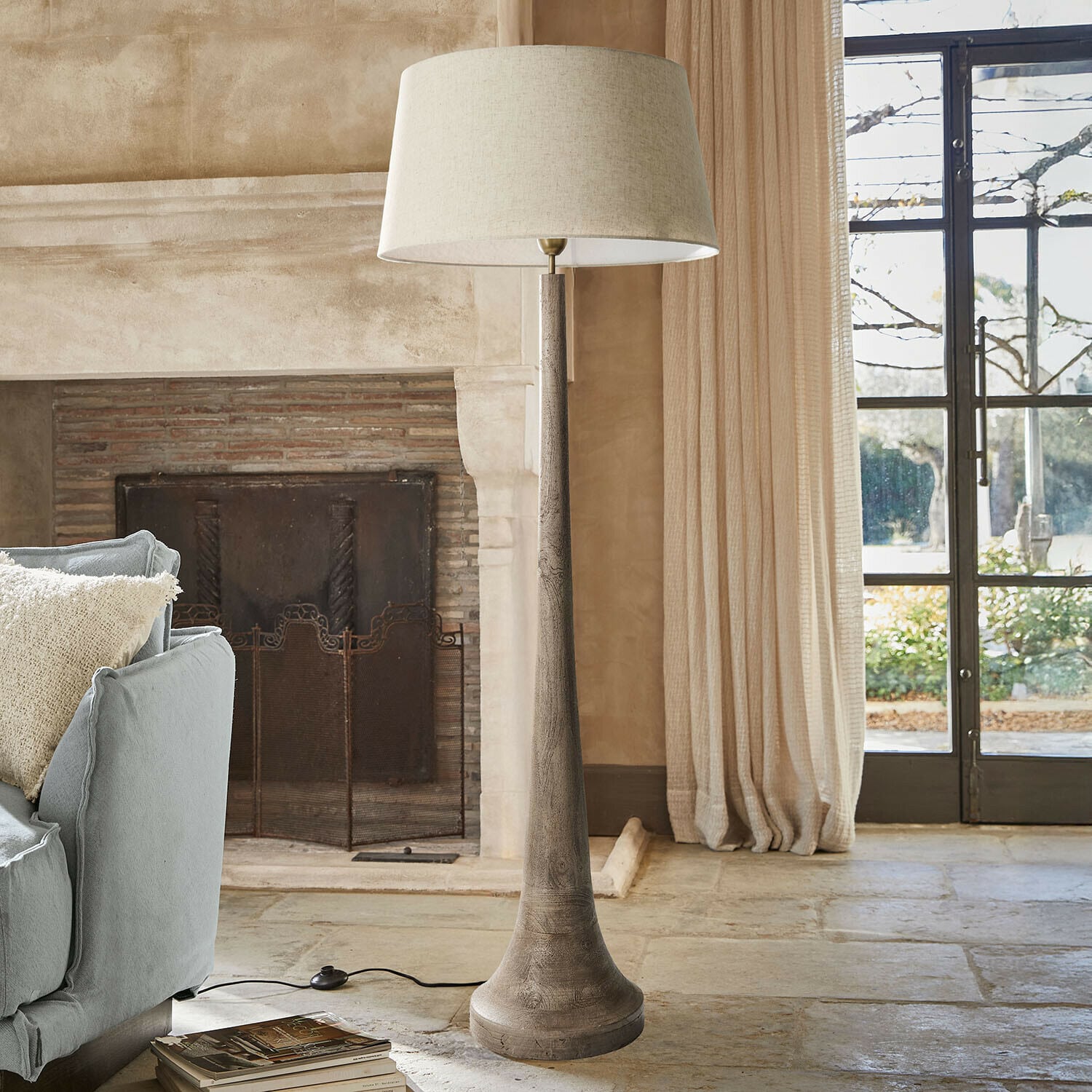 Lampe sur pied Helsfjord Lampadaire en bois avec abat-jour beige dans un salon chaleureux avec cheminée et canapé bleu