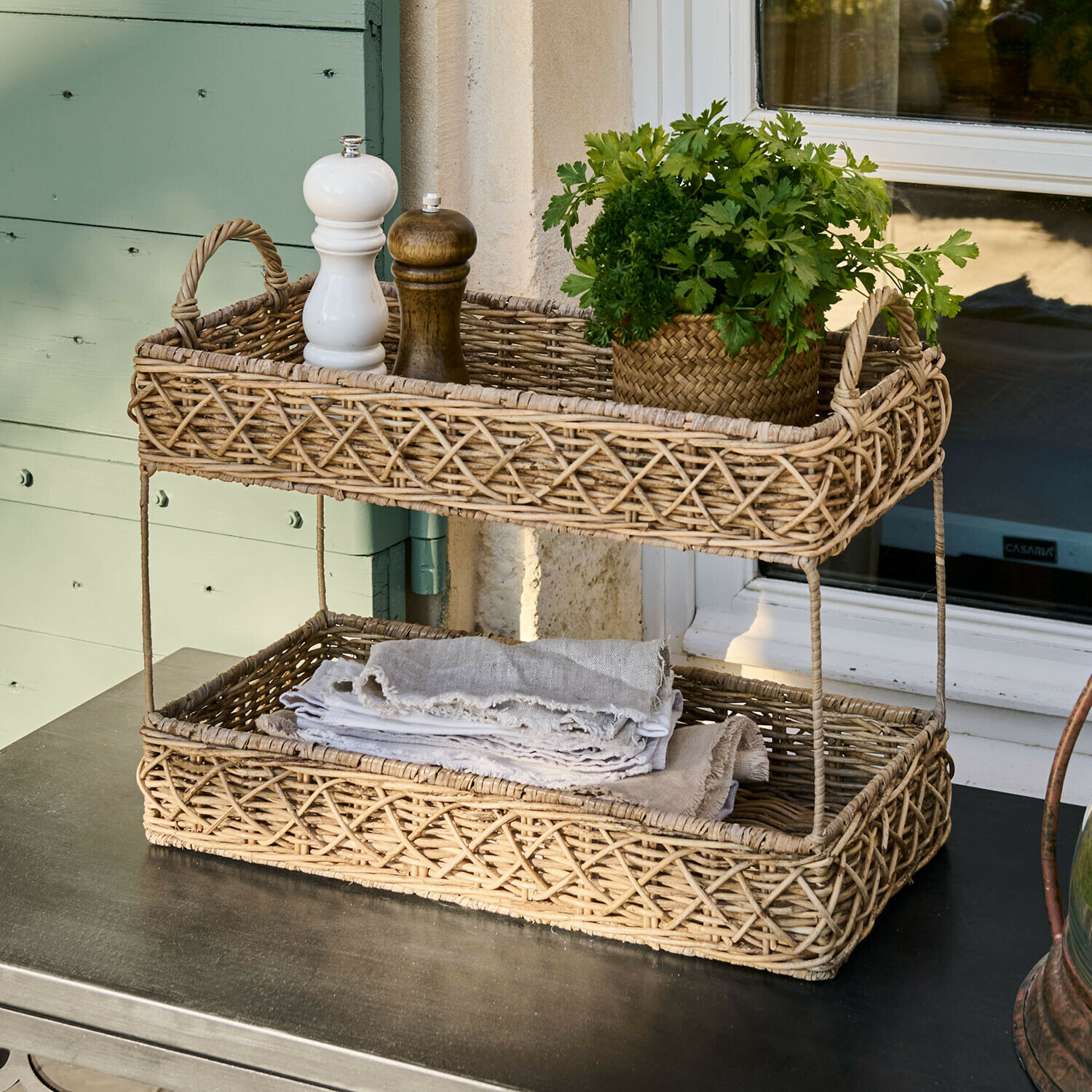 Panier à deux niveaux en rotin naturel avec épices et herbes fraîches sur une table