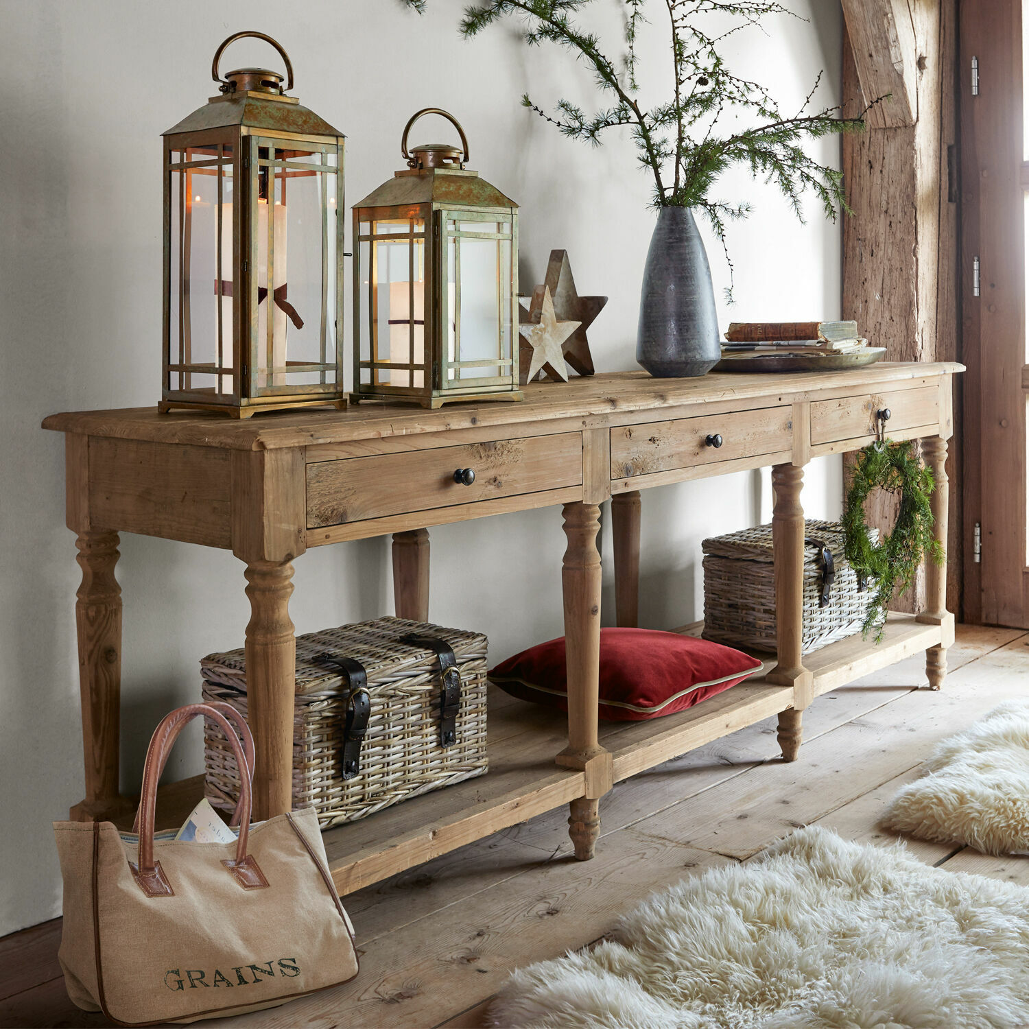 Console Misérieux Table console en bois avec trois tiroirs, lanternes décoratives et paniers en osier dans un intérieur chaleureux
