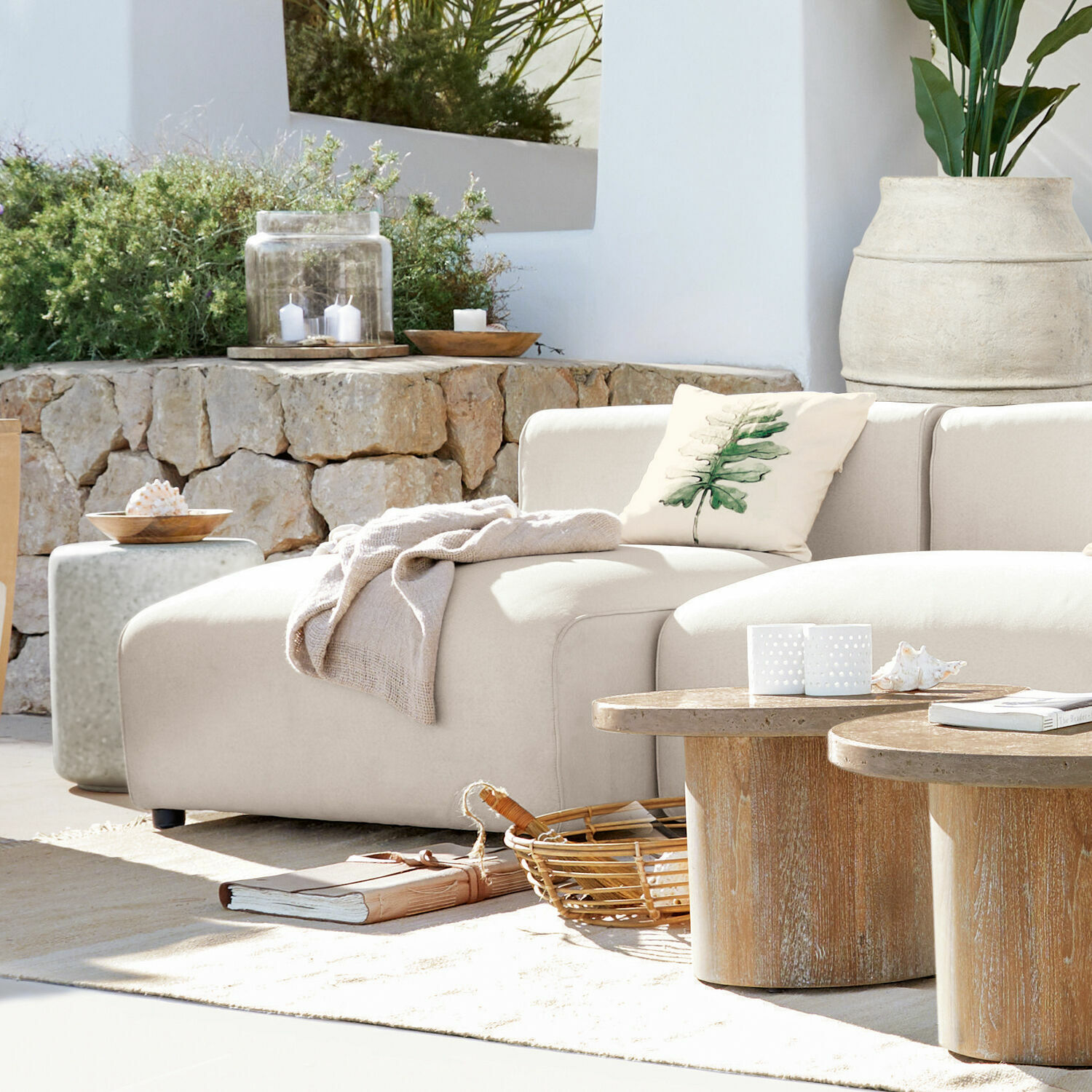 Canapé modulable Vézère Canapé beige en tissu avec coussin feuille et tables basses en bois dans un salon lumineux