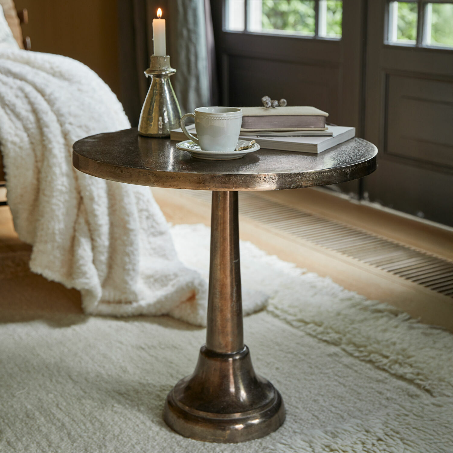Table d’appoint Bellevance Table d'appoint ronde en métal couleur laiton avec tasse, bougie et livres sur tapis moelleux