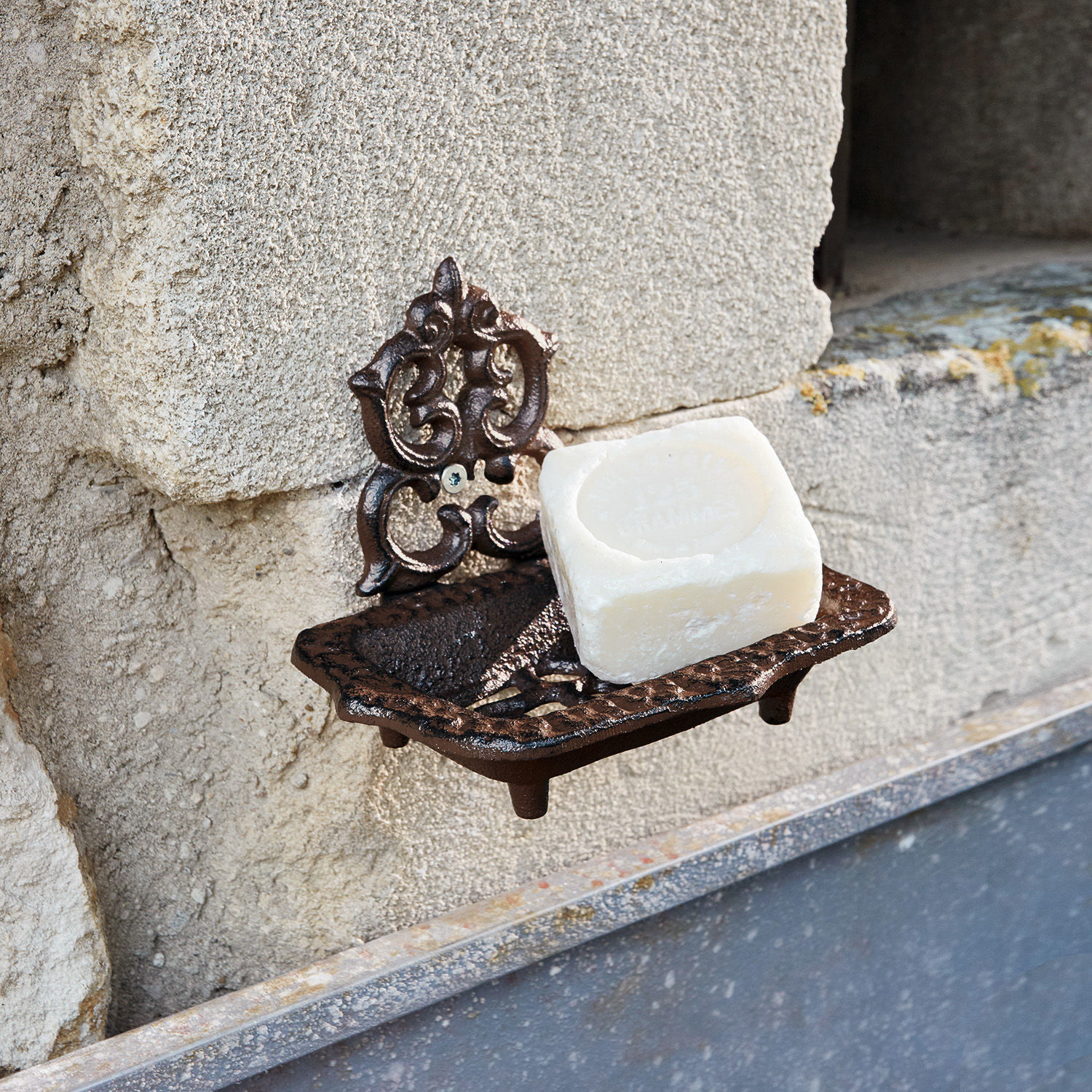 Porte-savon Moida Porte-savon mural en fonte marron avec savon blanc fixé sur un mur en pierre