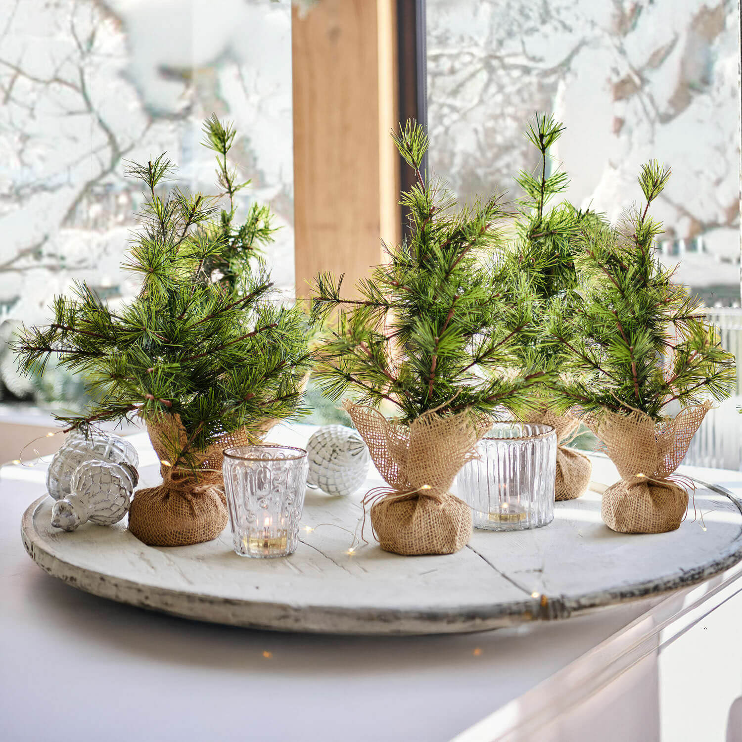 Lot de 4 sapins décoratifs Millies Petits sapins décoratifs en toile de jute sur un plateau blanc avec bougies et décorations de Noël