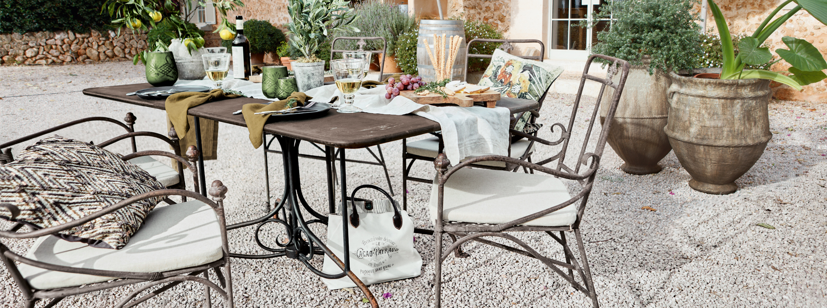 Table de jardin avec chaises en métal et décorations méditerranéennes sur patio en gravier