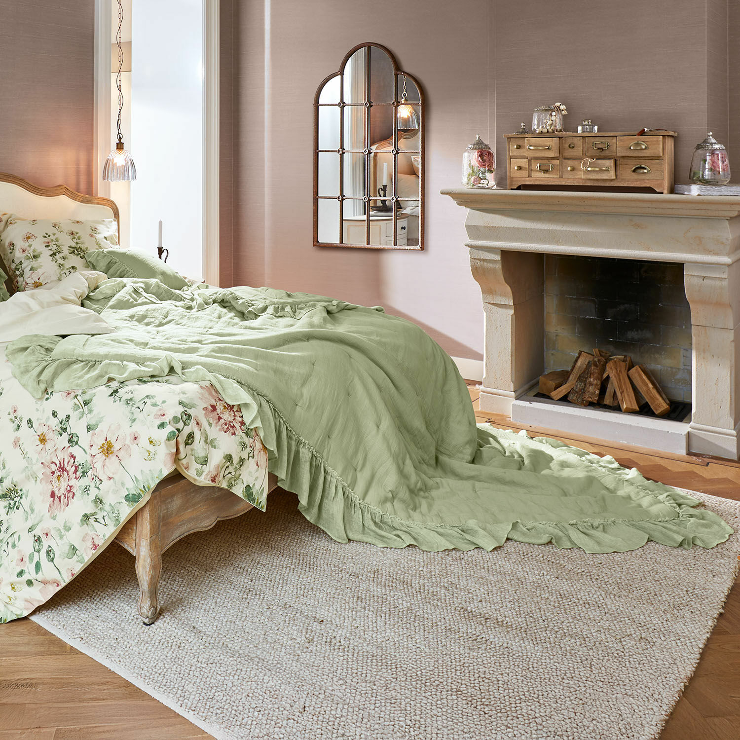 Courtepointe Martone Chambre avec lit en bois, couverture verte, linge de lit floral, tapis et cheminée décorative