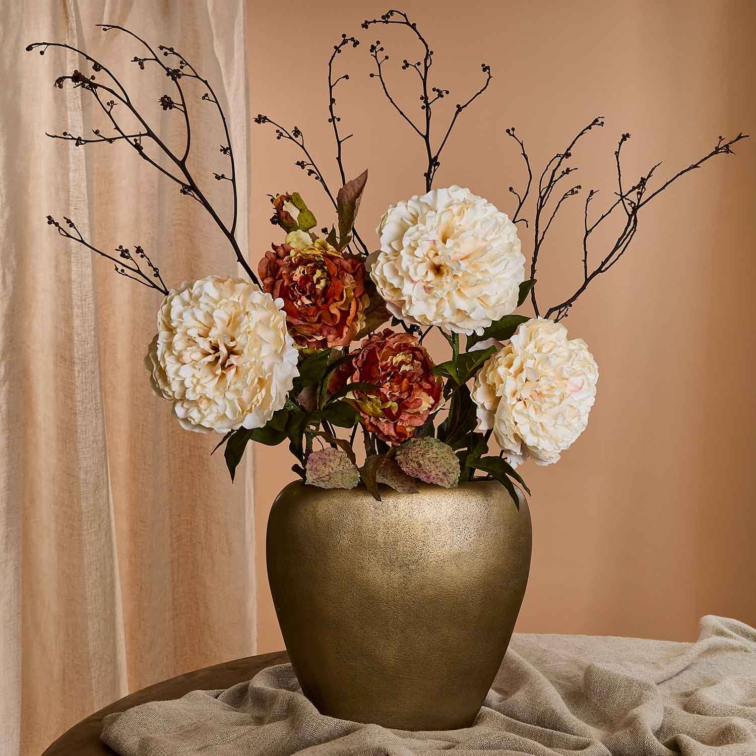 Bouquet de fleurs crème et marron dans un vase en céramique dorée sur fond beige