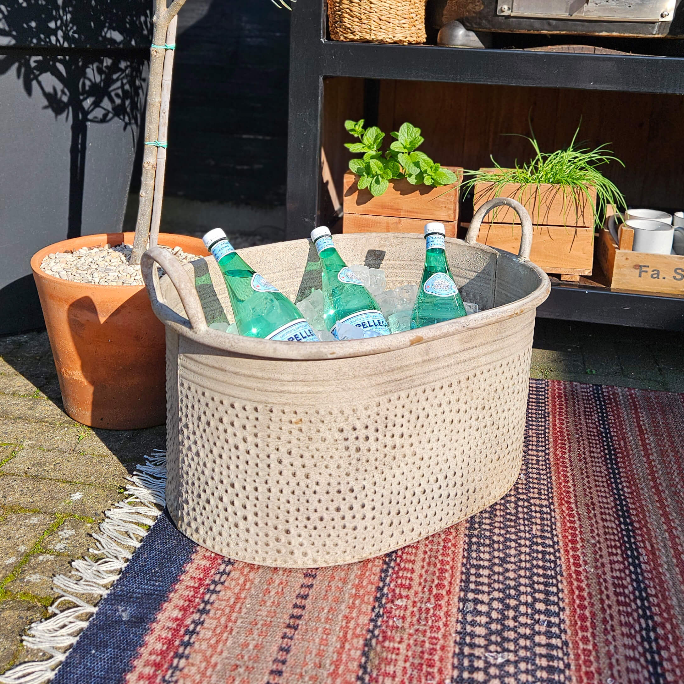 Panier beige en tissu avec poignées contenant des bouteilles d'eau minérale sur glace en extérieur