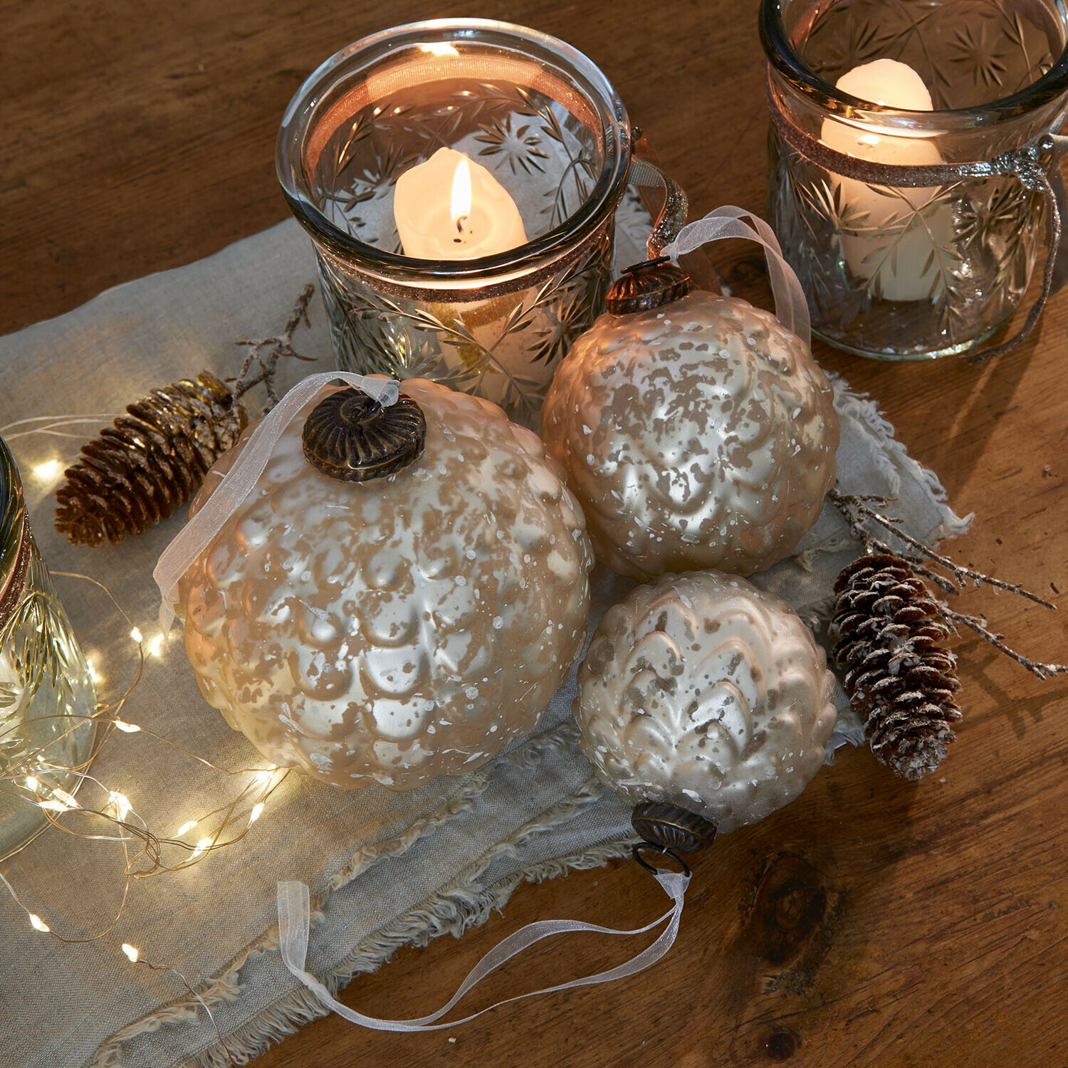 Lot de 6 boules de Noël Domara Ensemble de trois boules de Noël en verre nacré avec motif décoratif et bougies allumées en arrière-plan