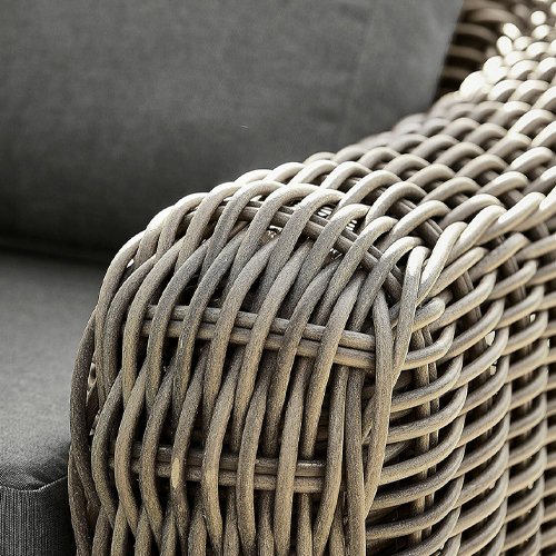 Détail d'un accoudoir en rotin synthétique marron sur un meuble d'extérieur avec coussin gris