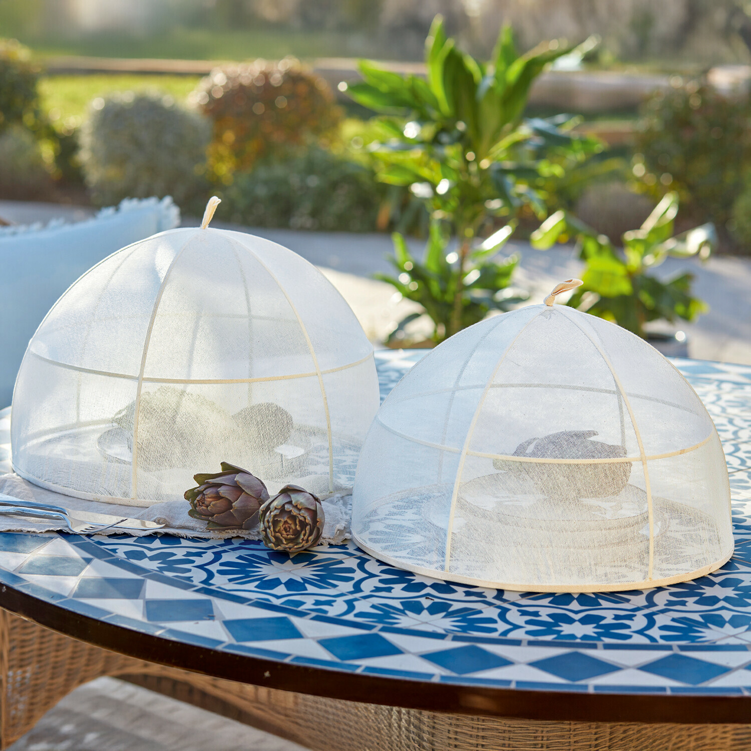 Lot de 2 cloches Ognéville Deux cloches alimentaires blanches en filet sur une table bleue à motifs, protection contre les insectes en extérieur