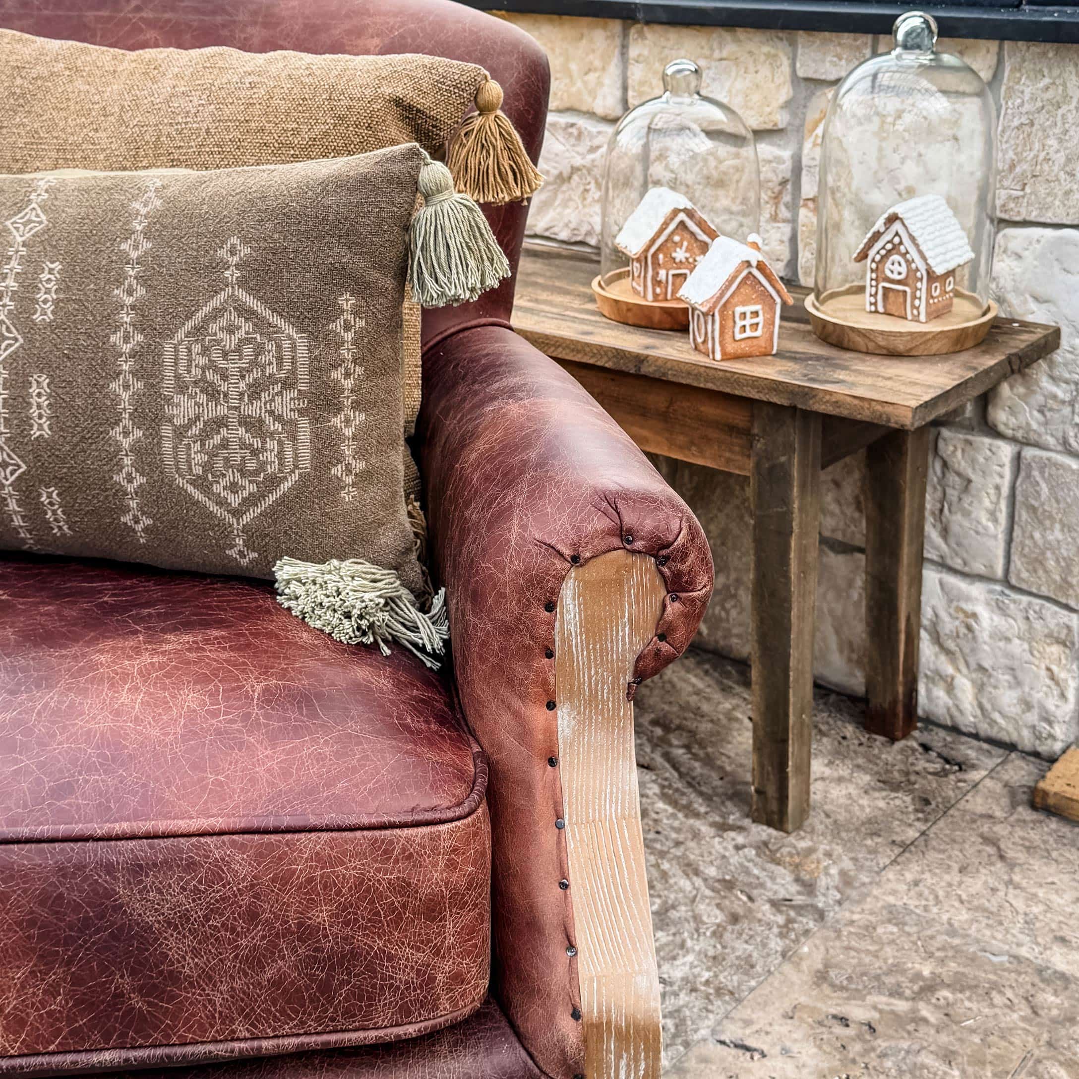 Canapé en cuir marron avec coussins décoratifs et table en bois avec décorations de Noël