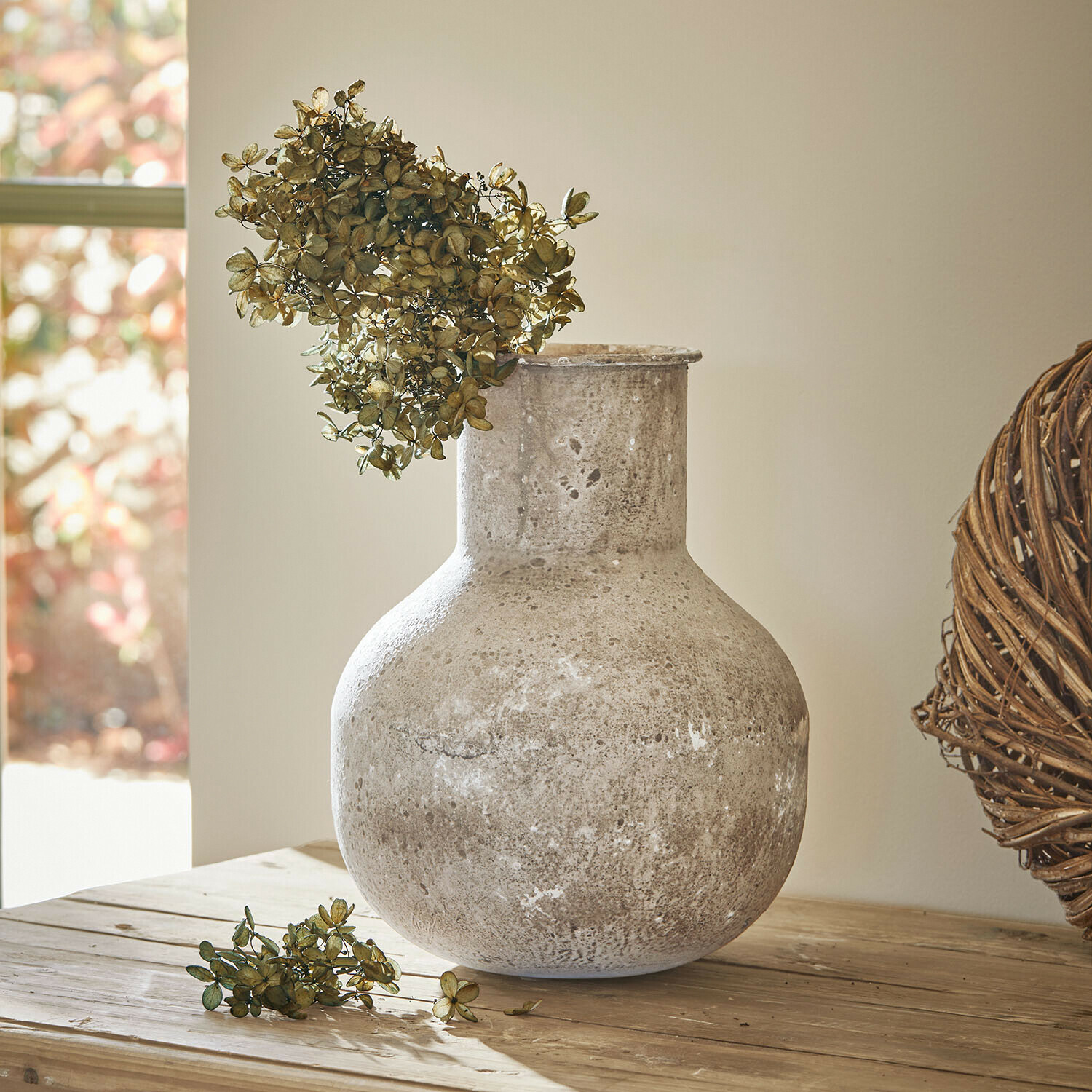 Vase Delavine Grand vase en céramique grise avec fleurs séchées sur une table en bois dans un intérieur lumineux