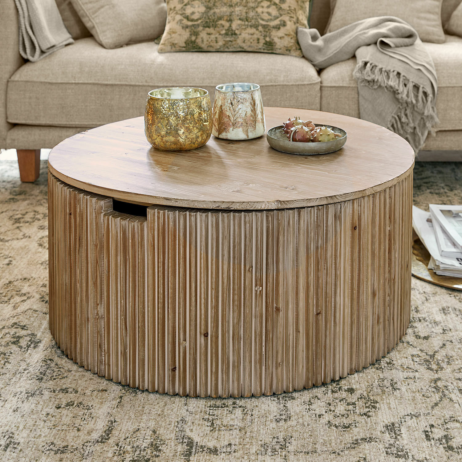 Table basse Saintouré Table basse ronde en bois naturel sur tapis dans un salon avec canapé beige et plaids