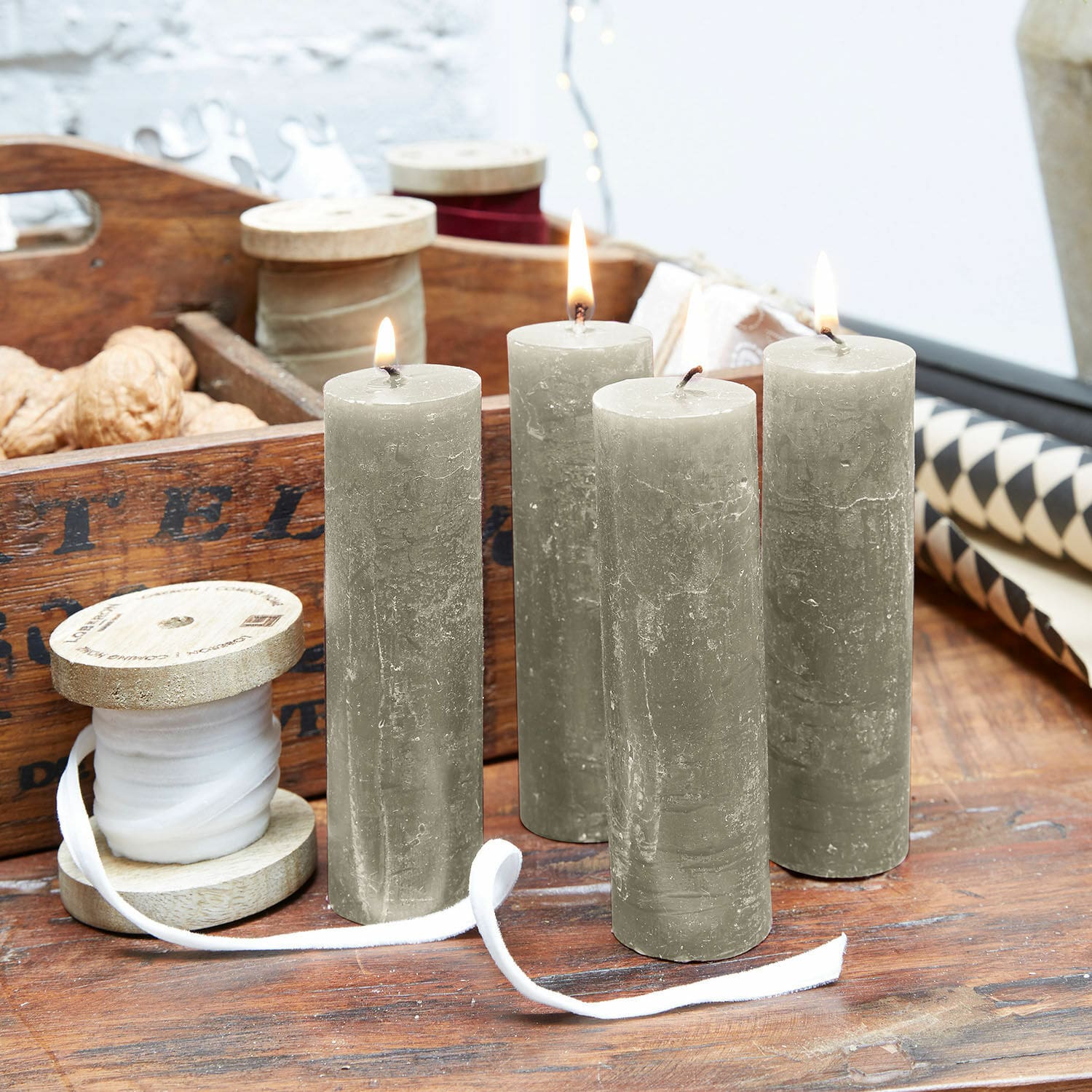 Lot de 4 bougies Muriel Quatre bougies cylindriques grises sur une table en bois avec une bobine en bois et des décorations