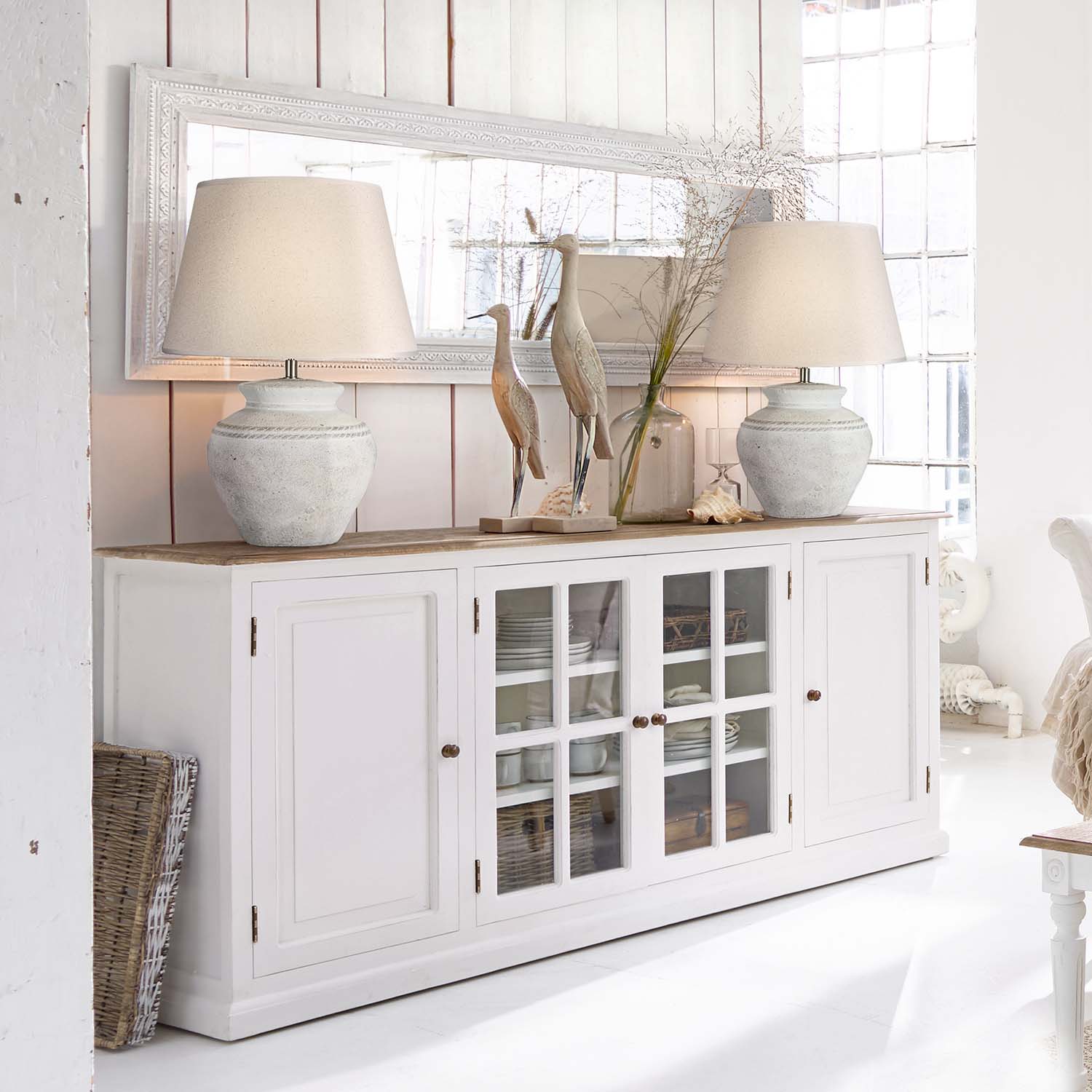Buffet en bois blanc avec portes vitrées et lampes en céramique dans un intérieur lumineux