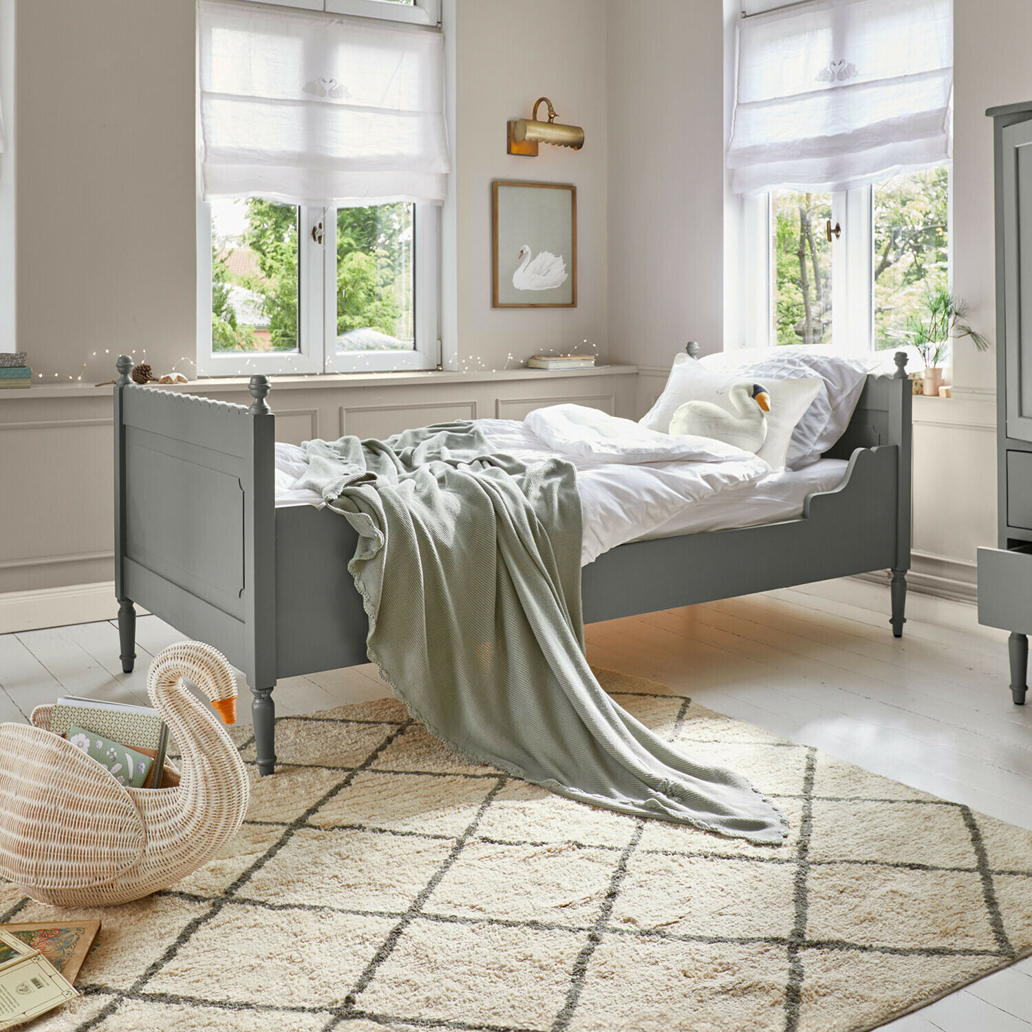 Lit simple Kystlund Lit en bois vert avec literie blanche et couverture grise dans une chambre lumineuse avec tapis à motifs