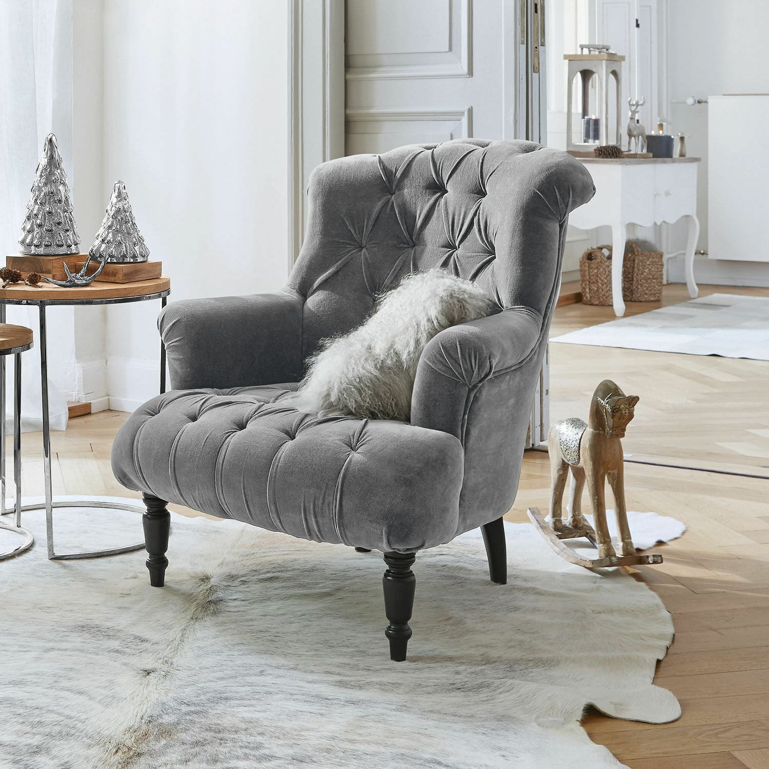 Fauteuil Parranquet Fauteuil gris en velours capitonné avec pieds en bois noir dans un salon lumineux décoré avec style