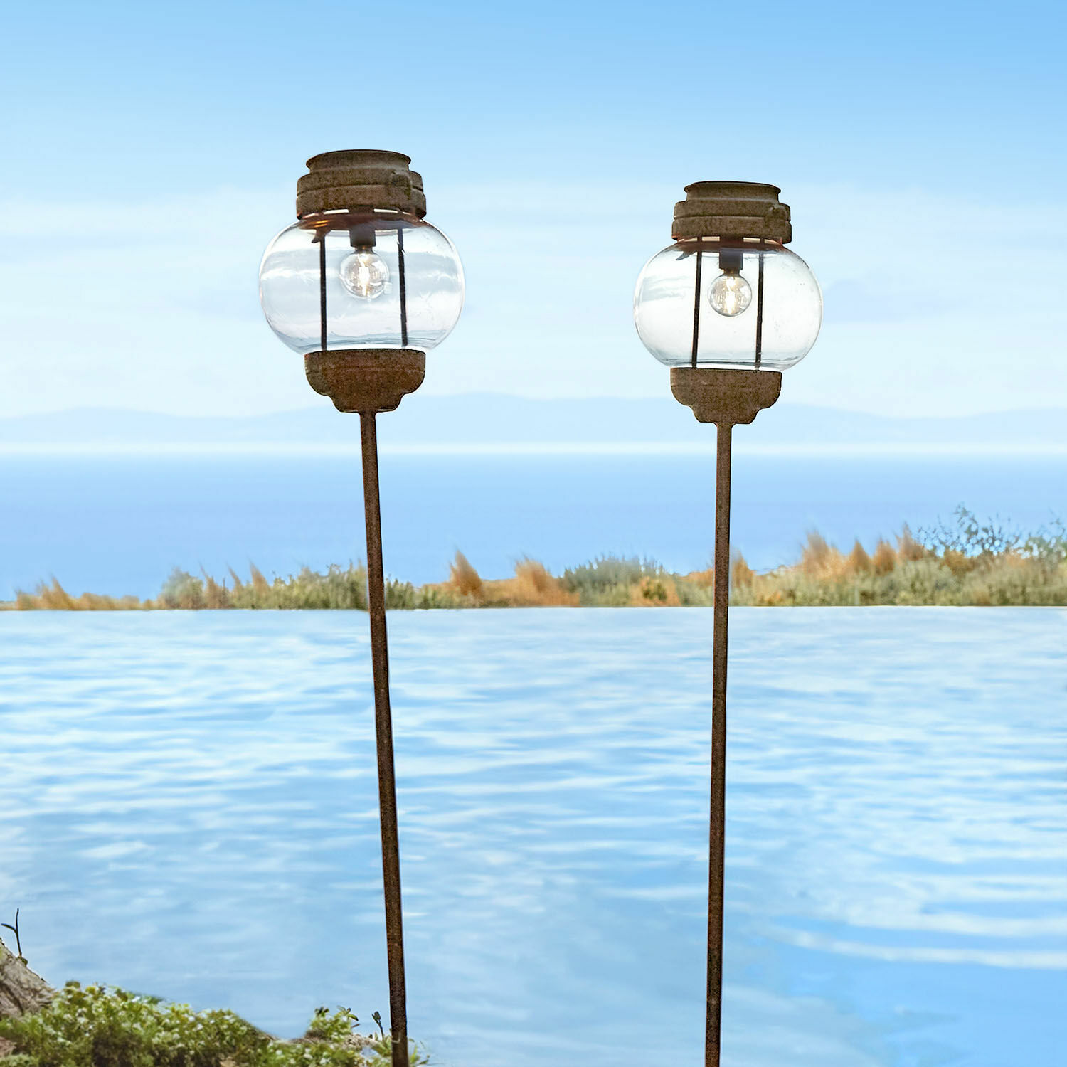 Lot de 2 lanternes solaires Nayalif Deux lanternes de jardin en verre et métal rouillé près d'une piscine avec vue sur la mer