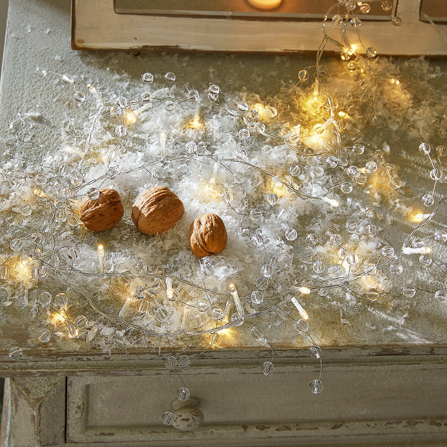 Lot de 2 guirlandes lumineuses Neviane Guirlande LED fine avec perles transparentes sur surface rustique avec des noix décoratives