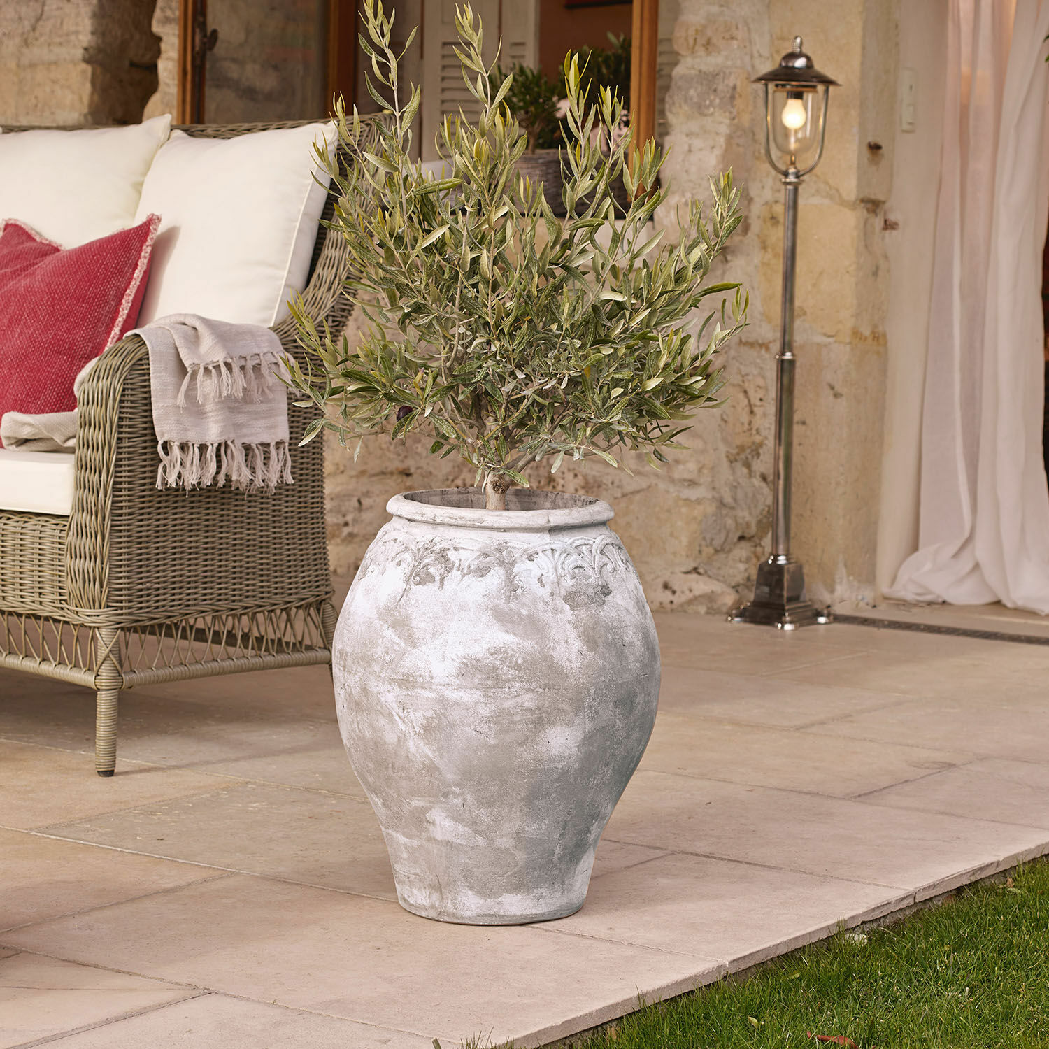 Cache-pot Donneville Grand vase en céramique grise avec plante sur terrasse près d'un canapé en osier avec coussins
