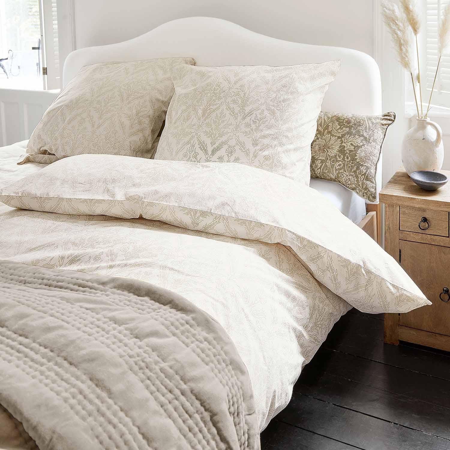 Parure de lit en coton clair avec motif végétal délicat et couverture douce dans une chambre lumineuse