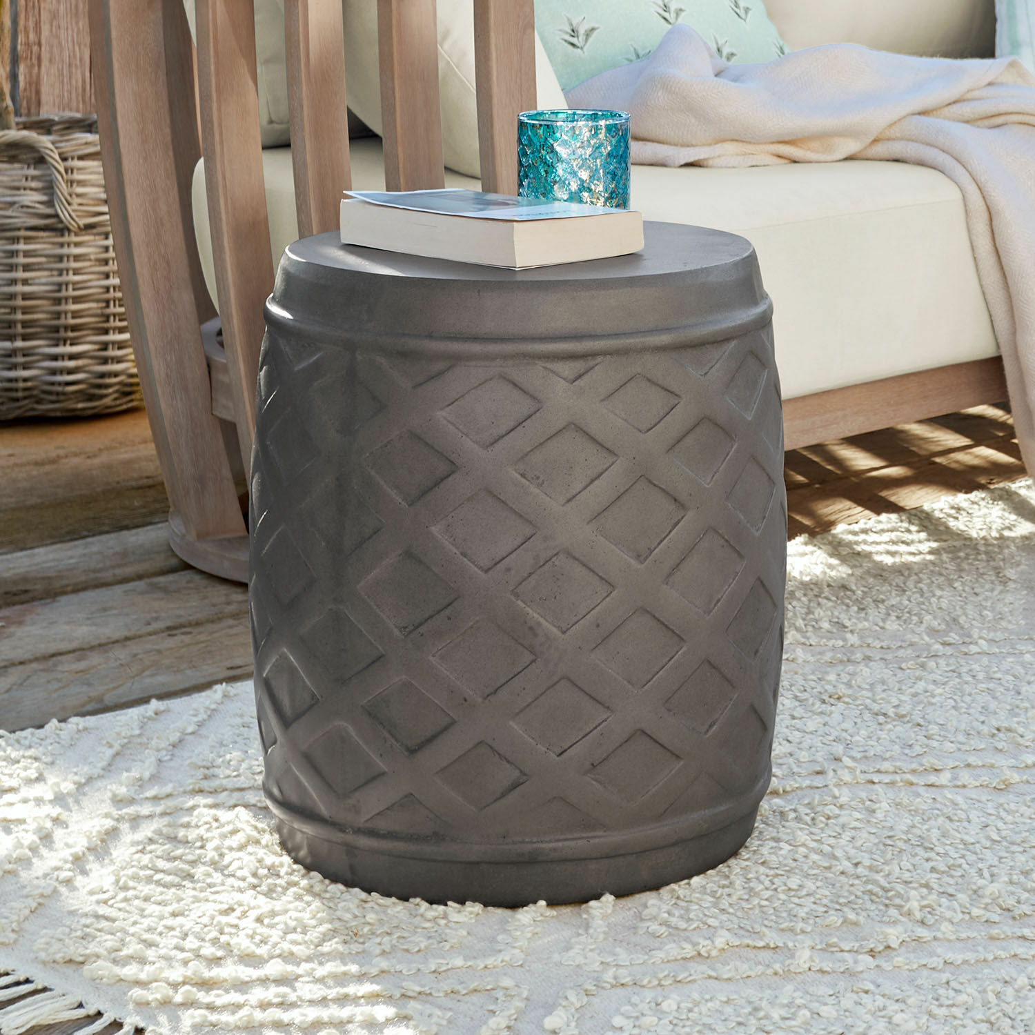 Tabouret Plévin Table d'appoint grise en béton avec motif géométrique sur tapis dans un salon avec meubles en bois