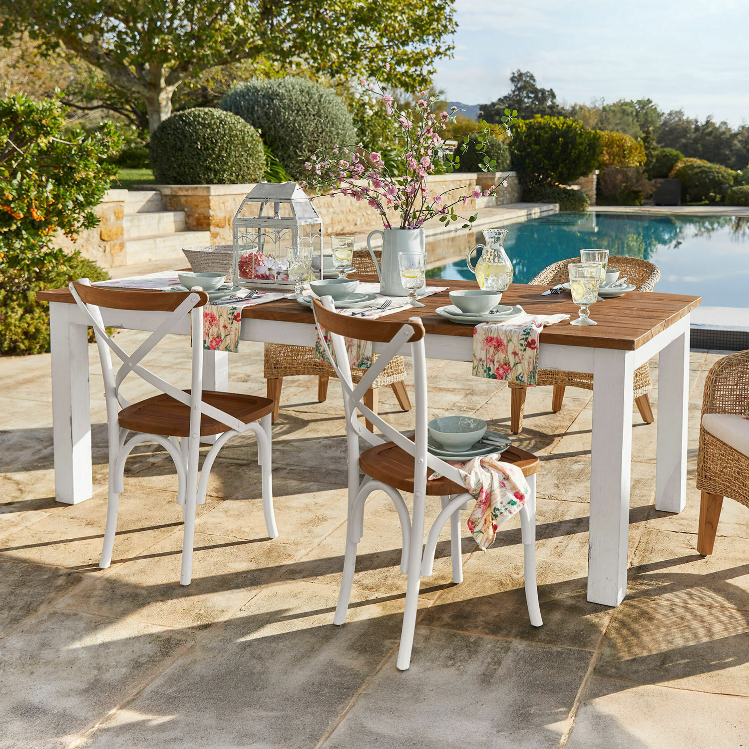 Table Kirkdale Table de jardin en bois avec pieds blancs et chaises rustiques près de la piscine
