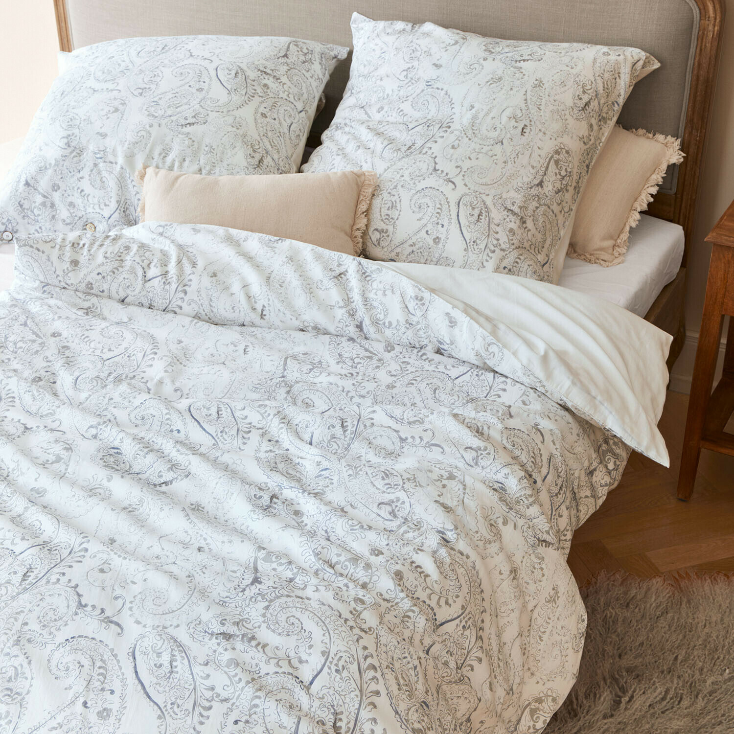 Parure de lit Caselia Parure de lit en coton avec motifs paisley clairs sur lit avec coussins décoratifs beige
