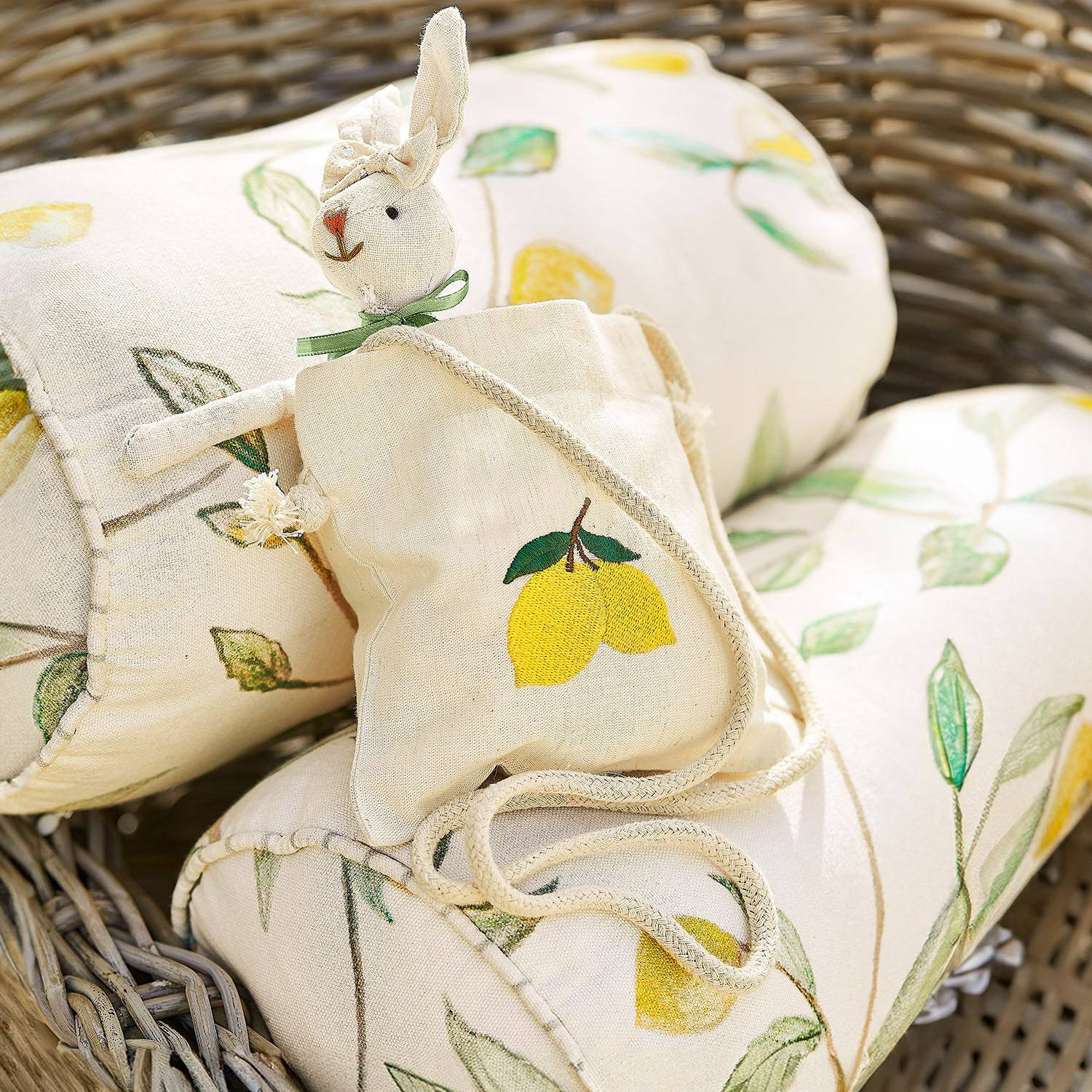 Pochette Palerina Sac en lin avec motif citron et lapin en peluche sur coussin à motif citron dans un panier en osier
