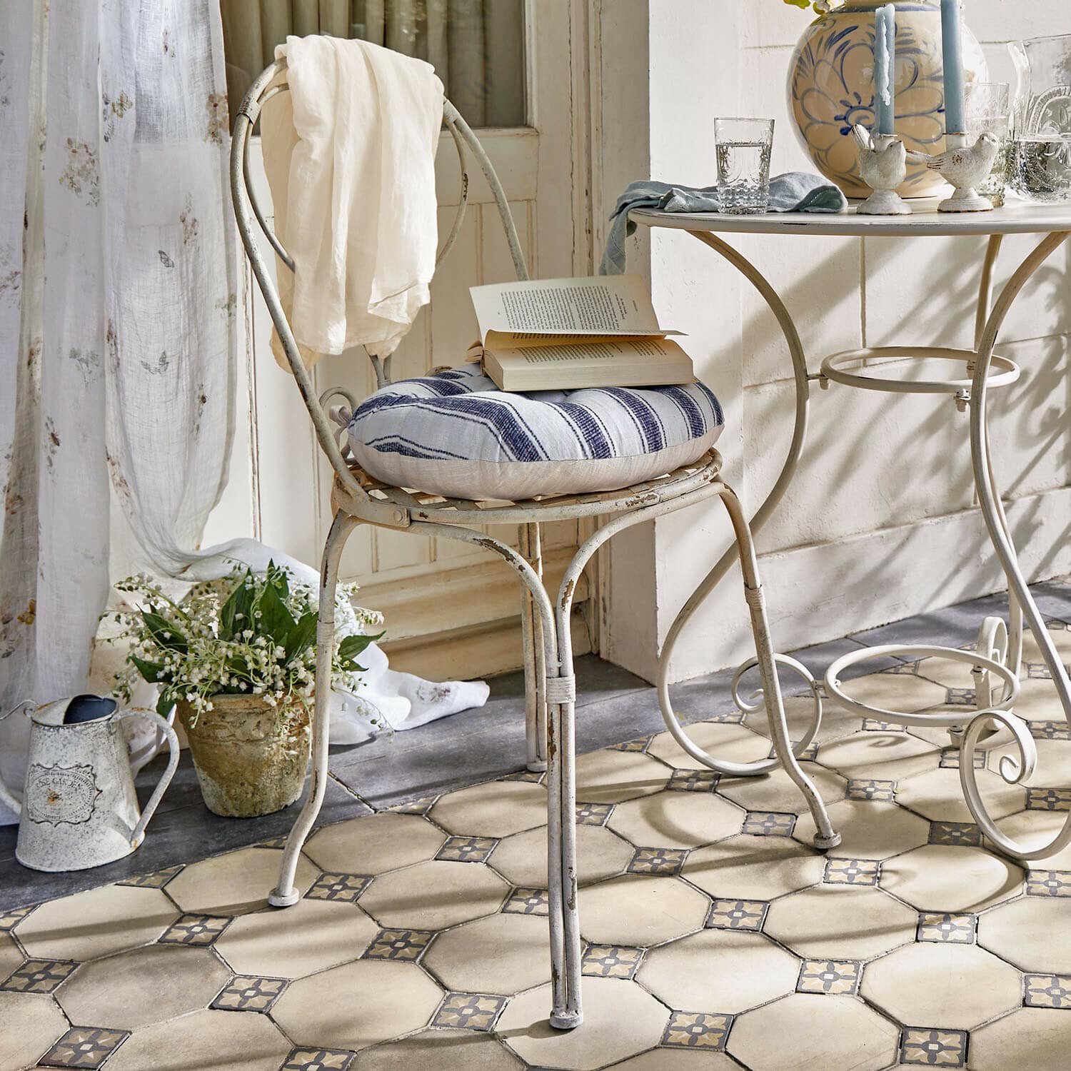Chaise Aube Chaise en métal vintage avec coussin rayé bleu et blanc, drap blanc sur dossier dans une pièce lumineuse