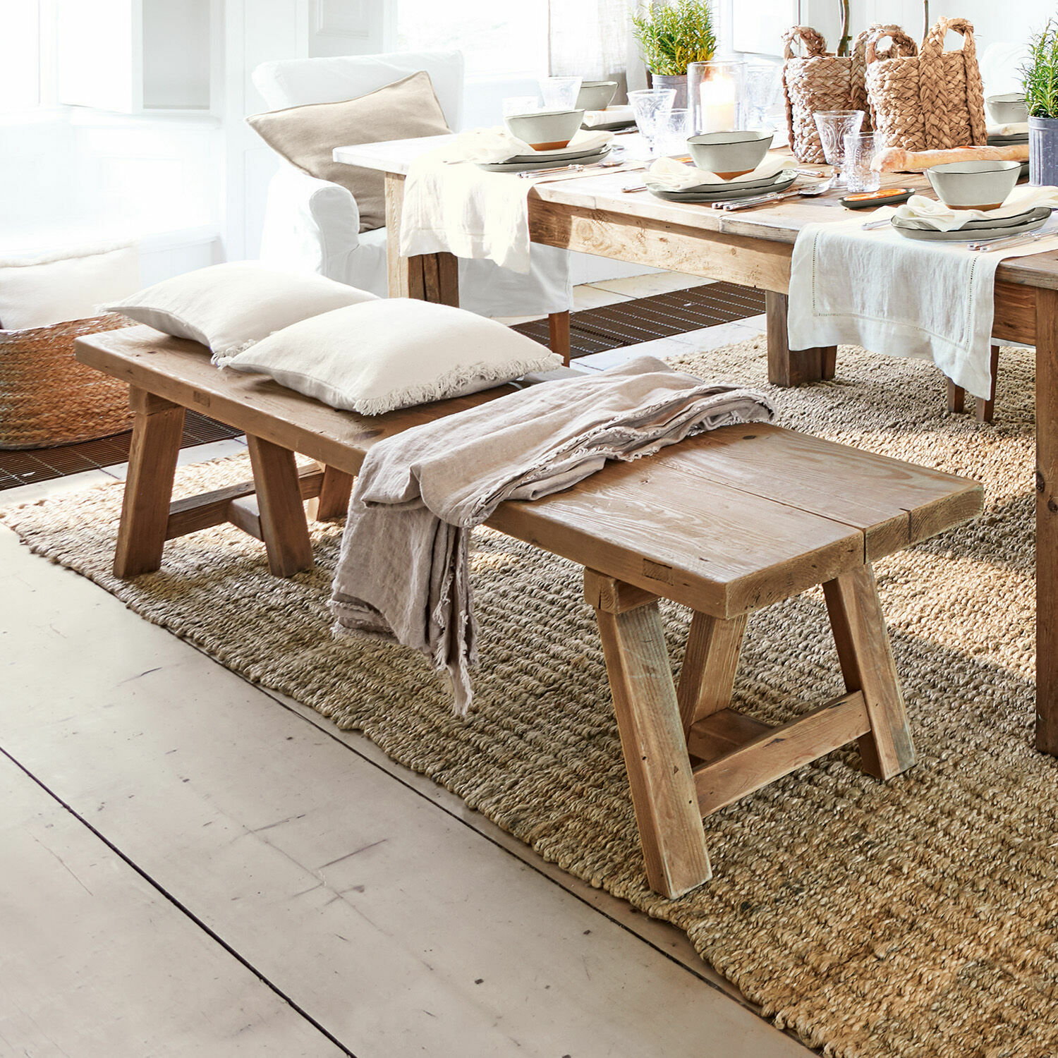 Banc Amherst Banc en bois naturel avec coussins et plaid sur tapis dans un salon lumineux et décoré