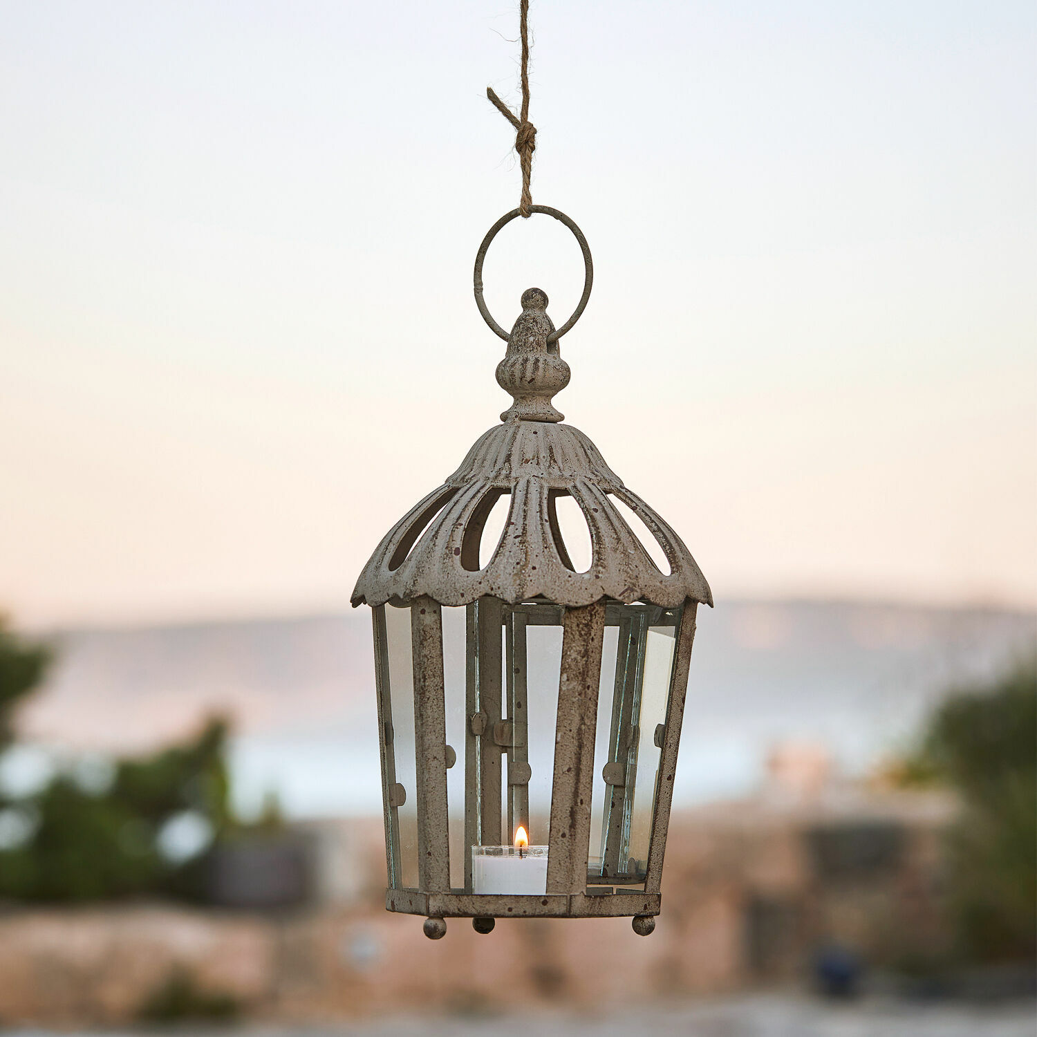 Lanterne Artemisie Lanterne suspendue en métal beige vieilli avec verre transparent et bougie allumée, style vintage.