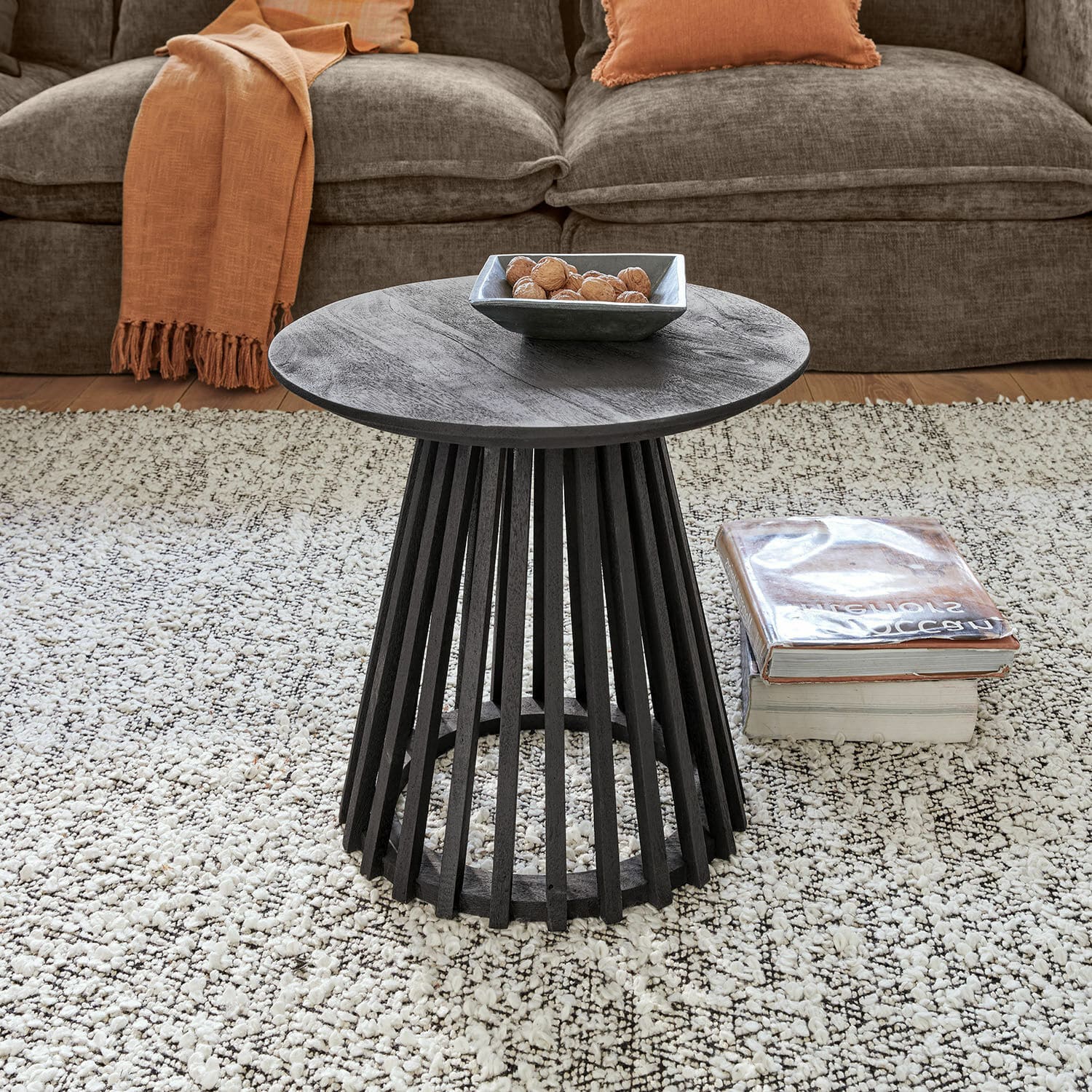 Table d’appoint Montaril Table basse ronde en bois noir avec base ajourée sur tapis clair dans un salon cosy