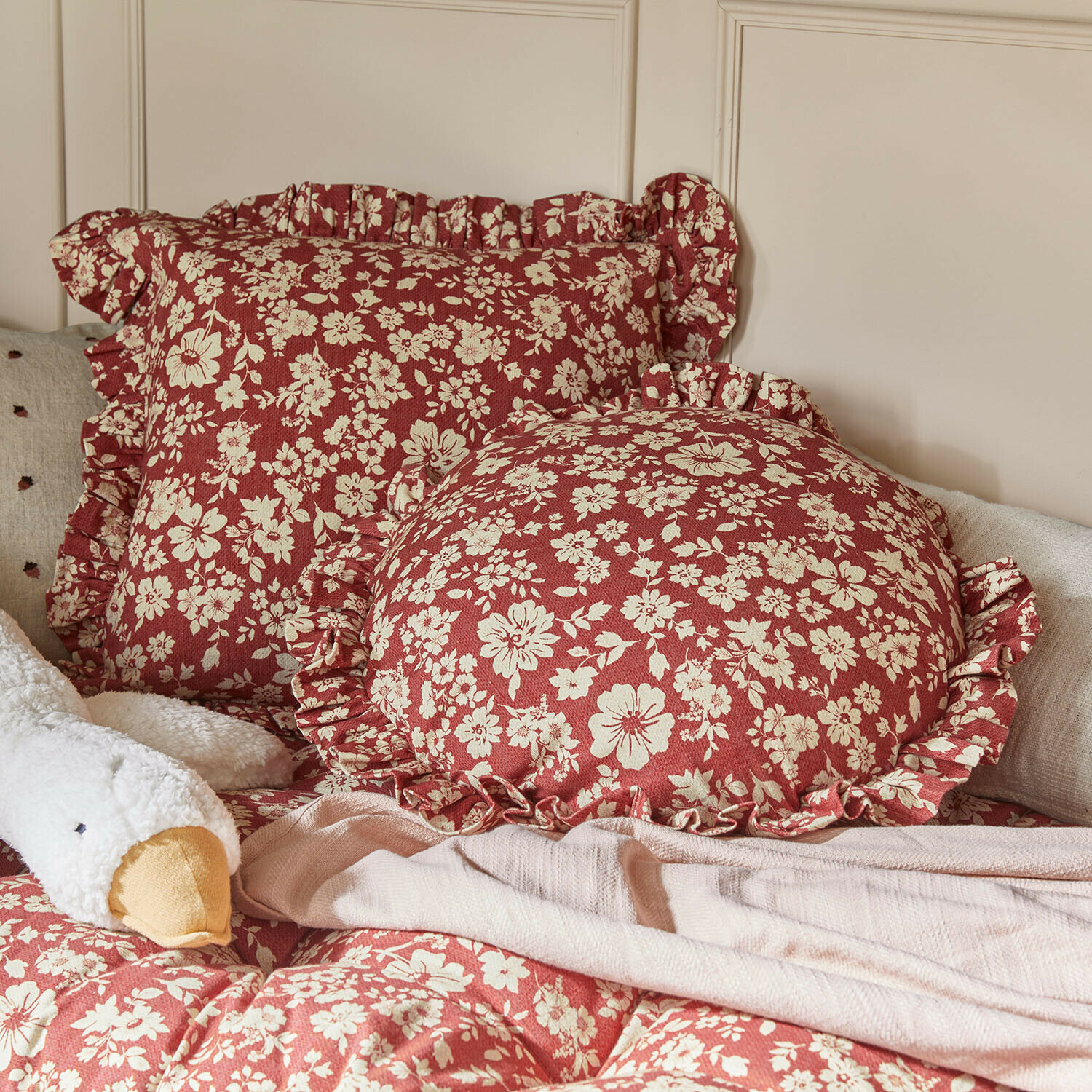 Lot de 2 coussins Frambelle Coussins rouges à motif floral crème avec volants sur un lit avec une couverture douce