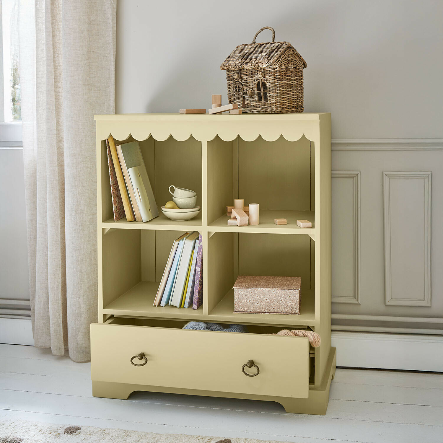 Commode beige en bois avec quatre compartiments et tiroir, panier en osier décoratif sur le dessus