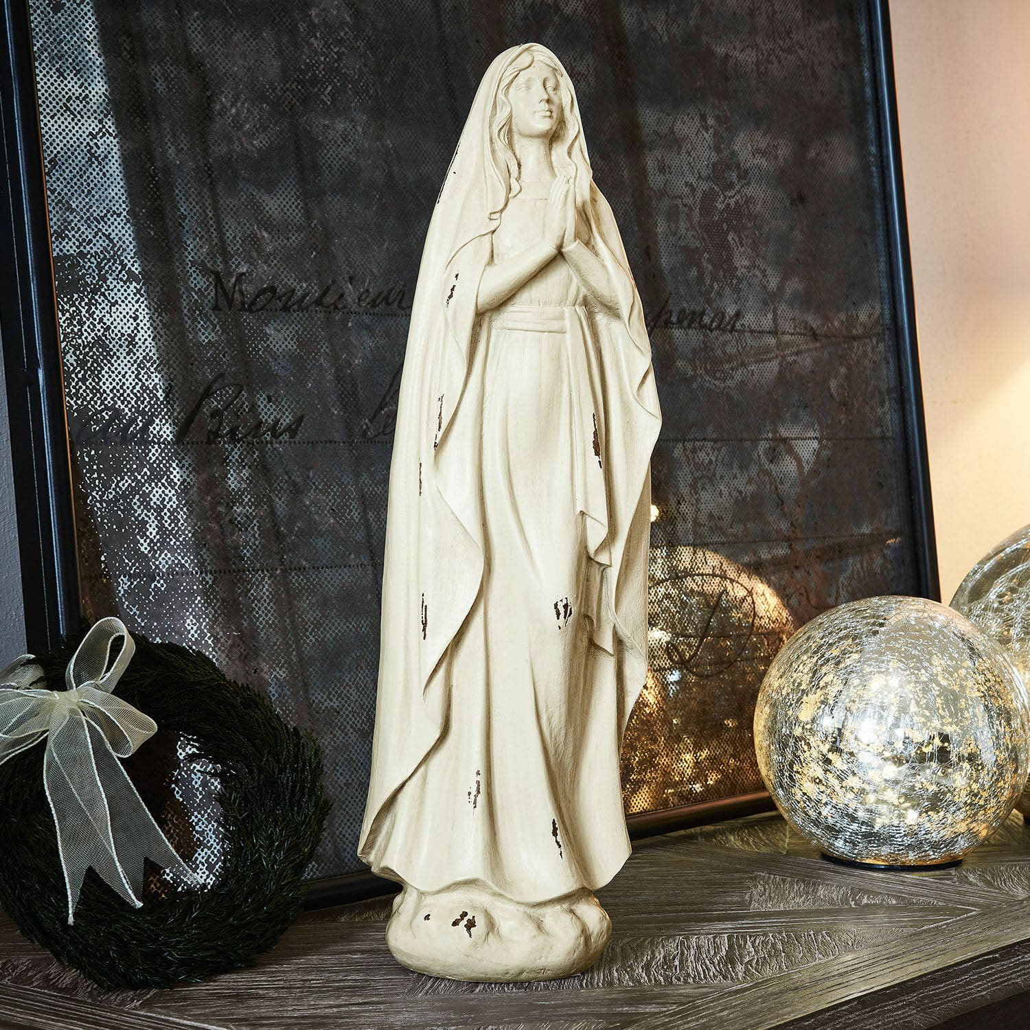 Statuette Antiere Statue décorative de la Vierge en matériau clair avec effet vieilli posée sur une table avec décorations de Noël