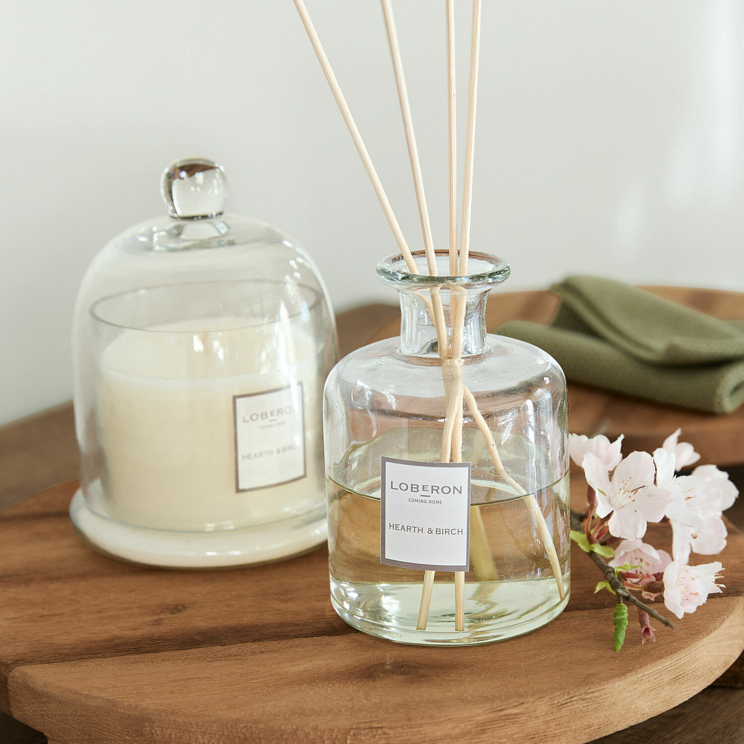 Coffret de senteurs Vanis Diffuseur de parfum en verre Hearth & Birch avec bâtonnets sur table en bois et bougie blanche sous cloche