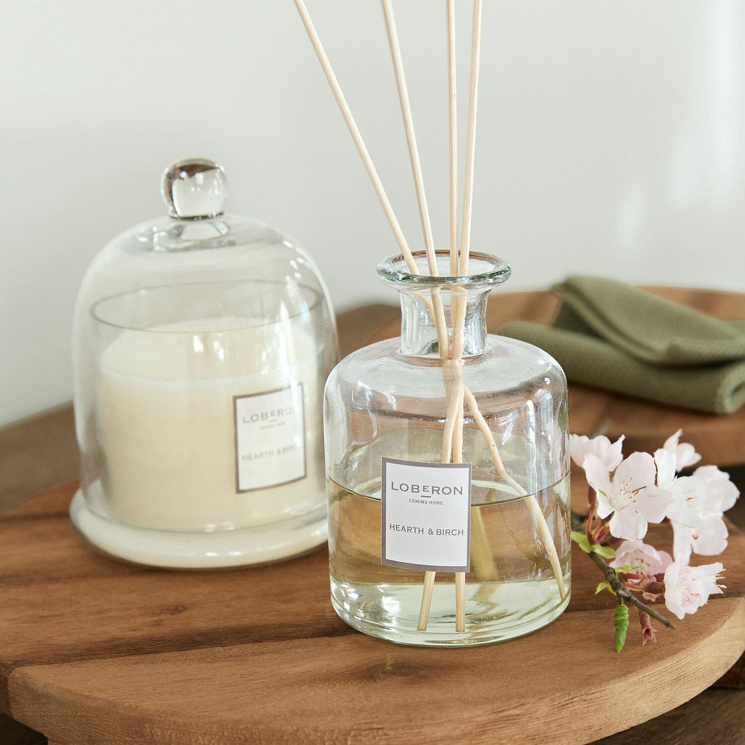 Coffret de senteurs Vanis Diffuseur de parfum en verre Hearth & Birch avec bâtonnets sur table en bois et bougie blanche sous cloche