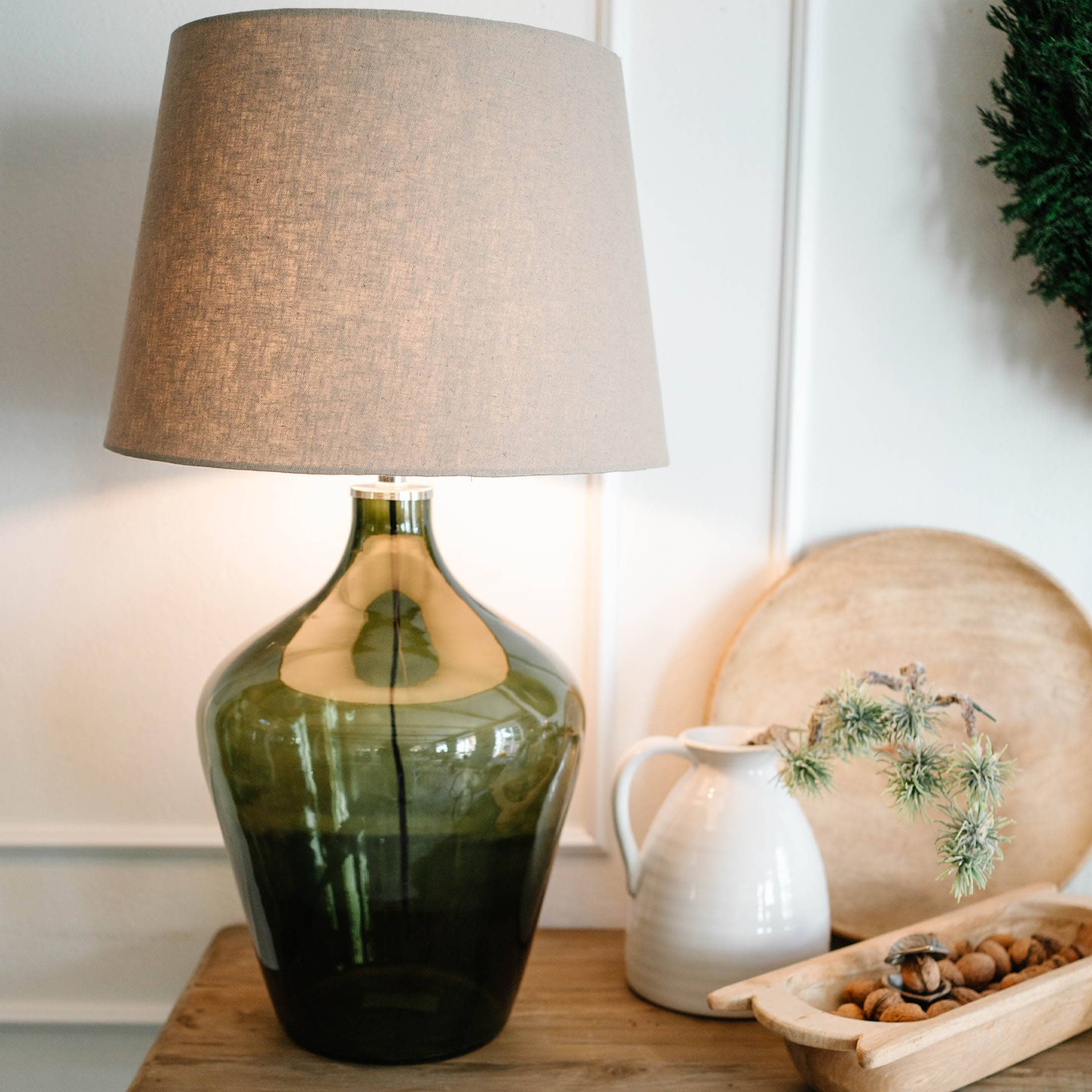 Lampe de table en verre vert avec abat-jour beige sur table en bois avec décorations
