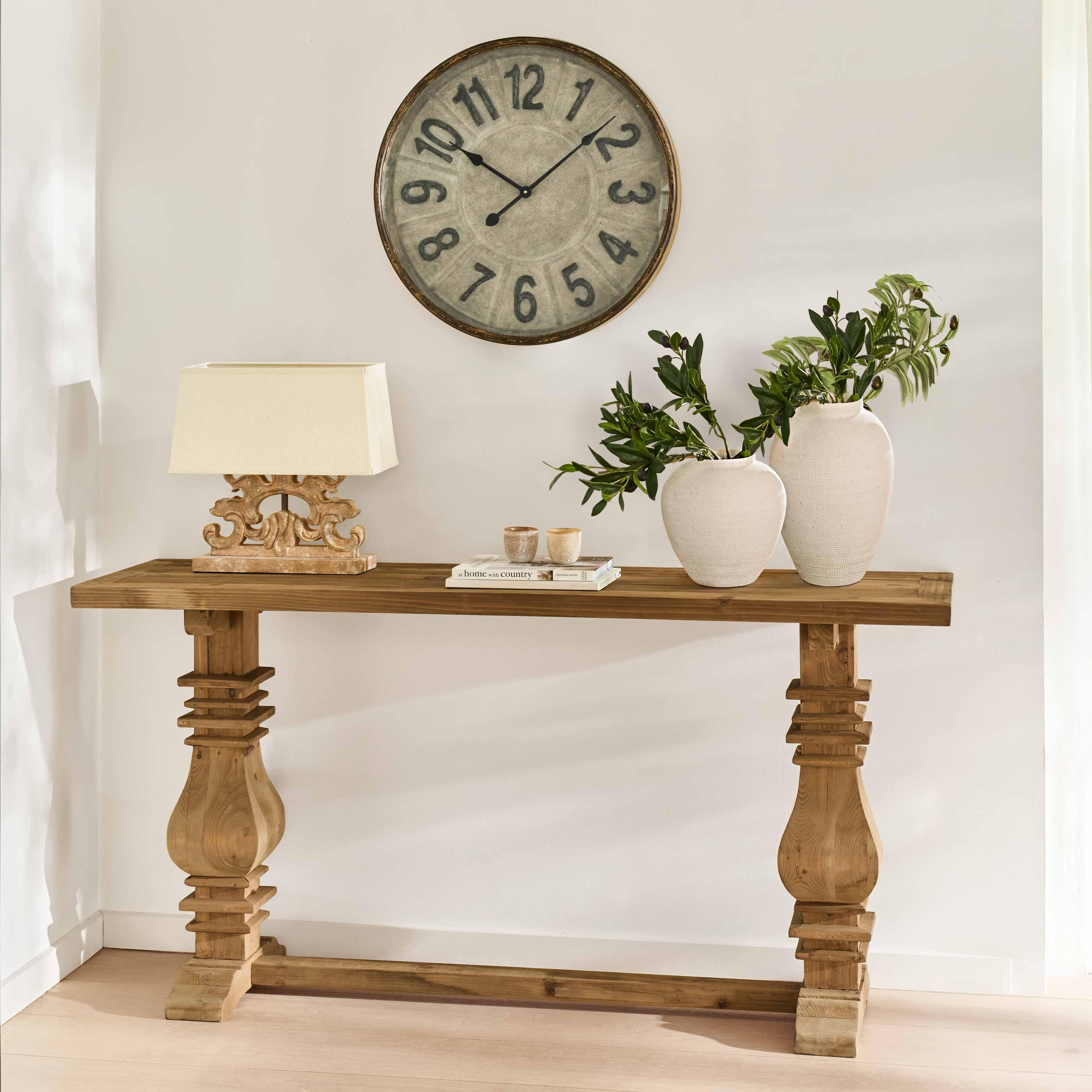 Console en bois massif avec pieds sculptés, vases blancs en céramique et lampe décorative sur fond clair