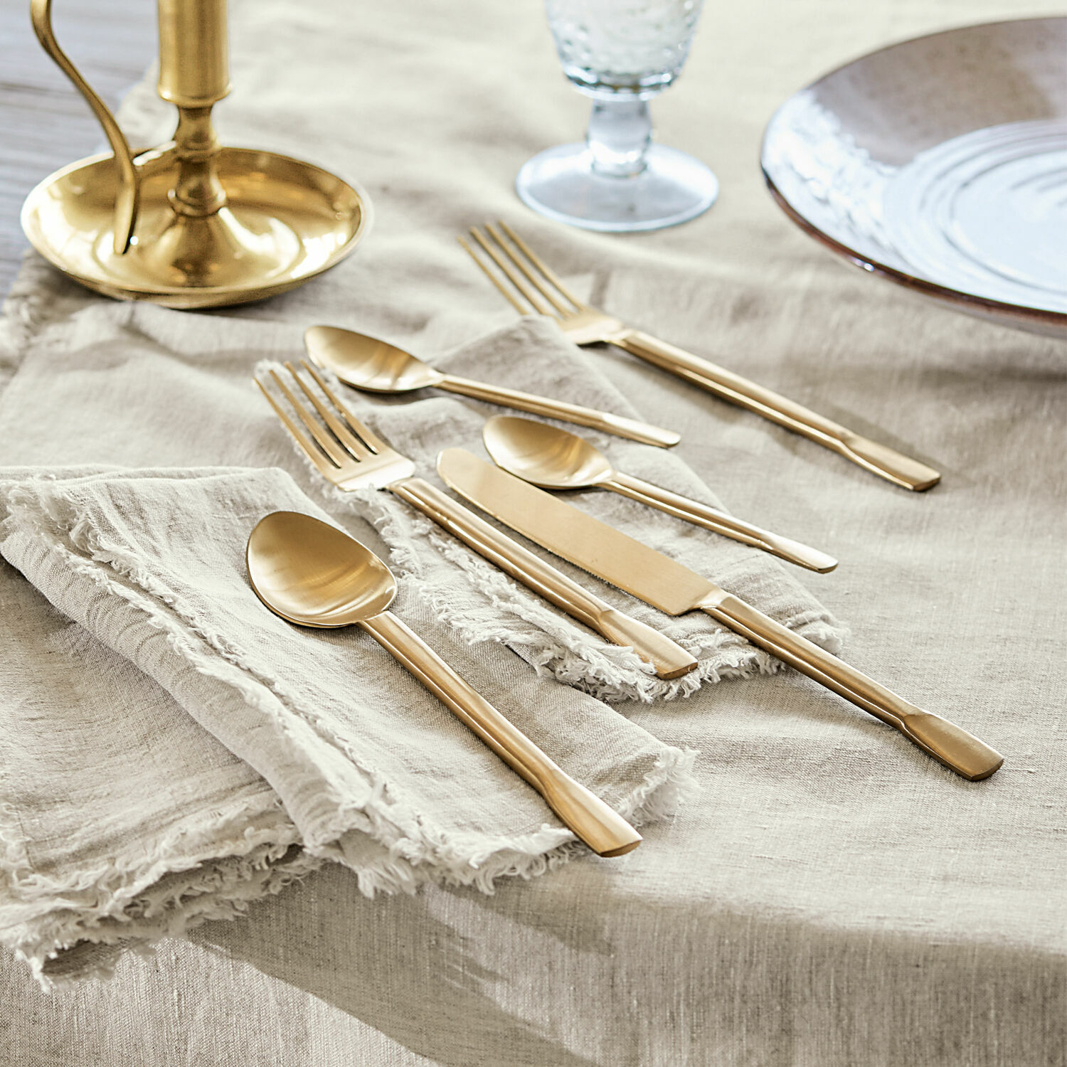 Couverts Malroy Service de couverts dorés en acier inoxydable sur nappe en lin pour une table élégante